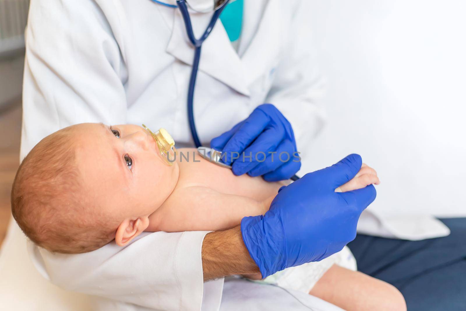 The doctor listens to the baby with a stethoscope. Selective focus. People.