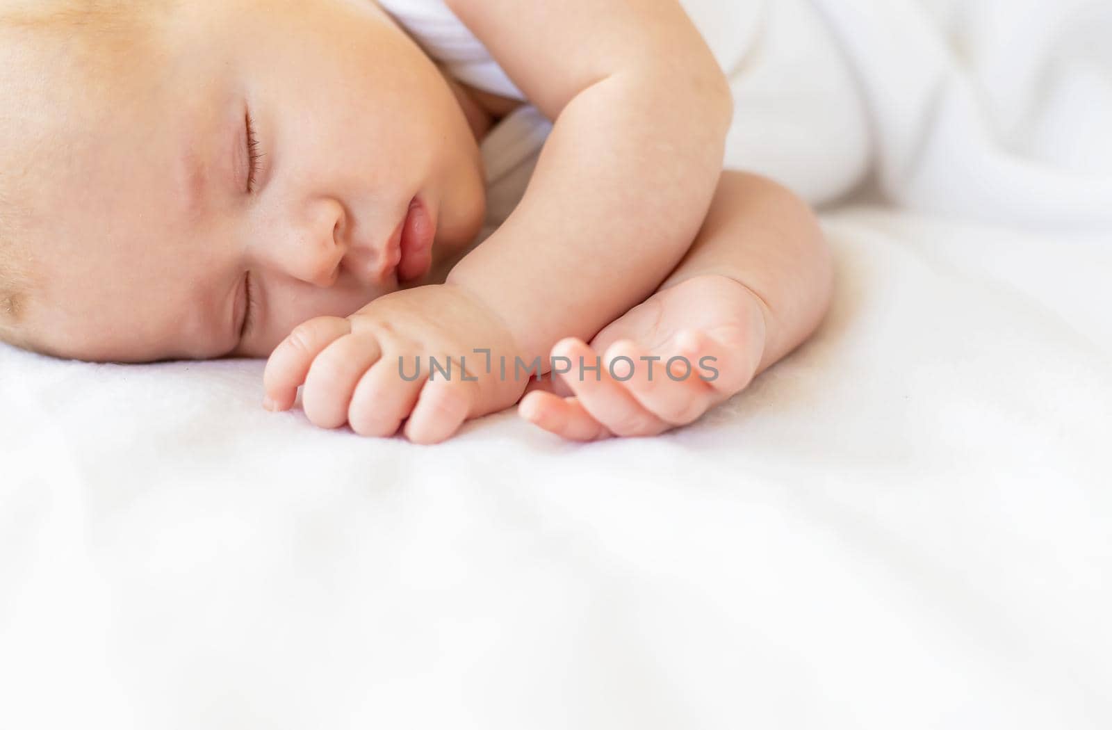 Baby sleeps against white background. Selective focus. People.