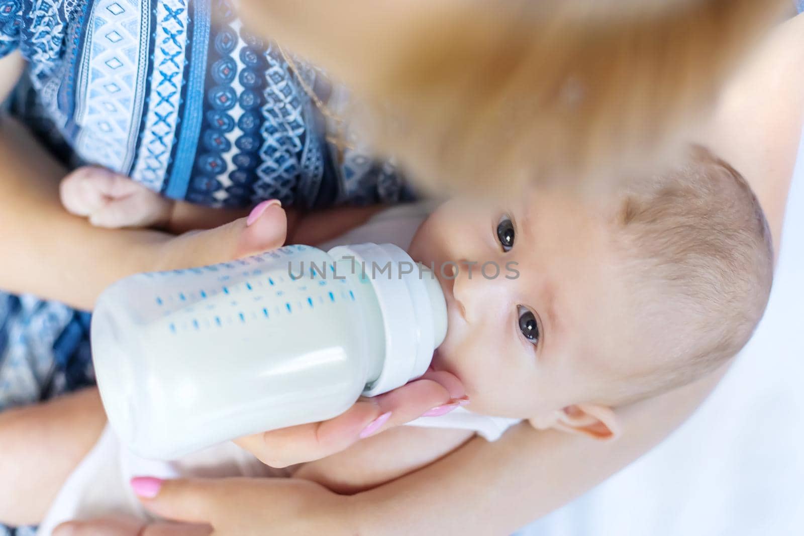 Mom feeds the baby with a bottle. Selective focus. People.