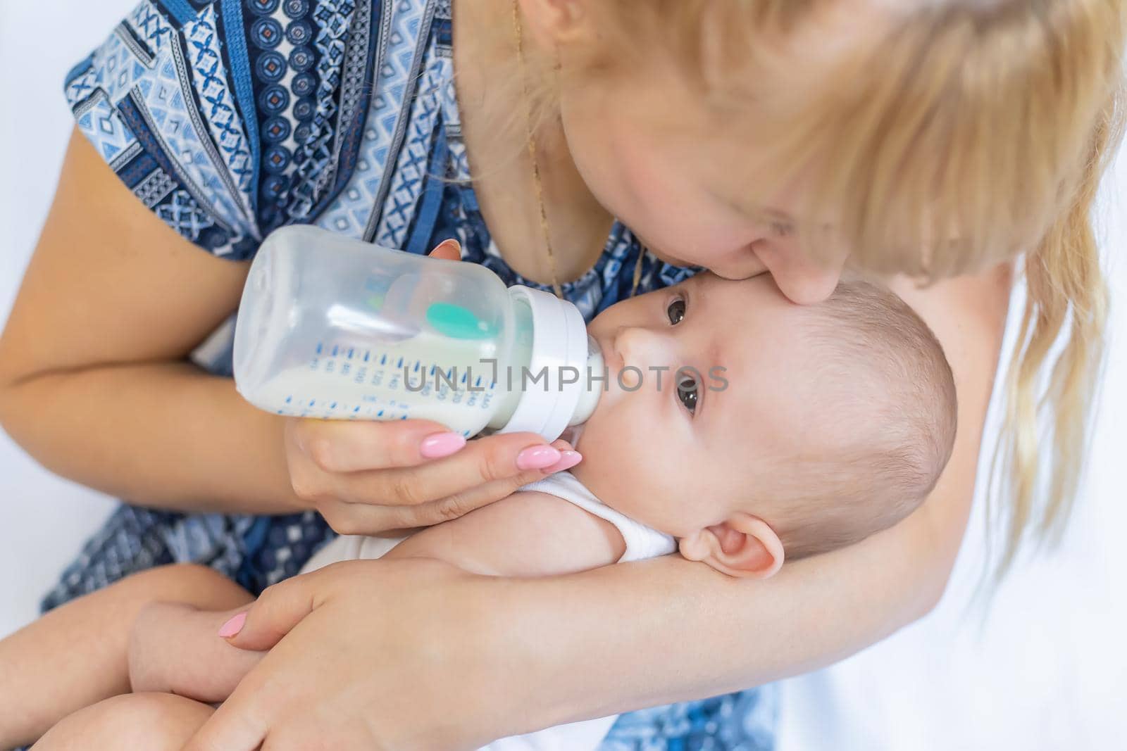 Mom feeds the baby with a bottle. Selective focus. People.