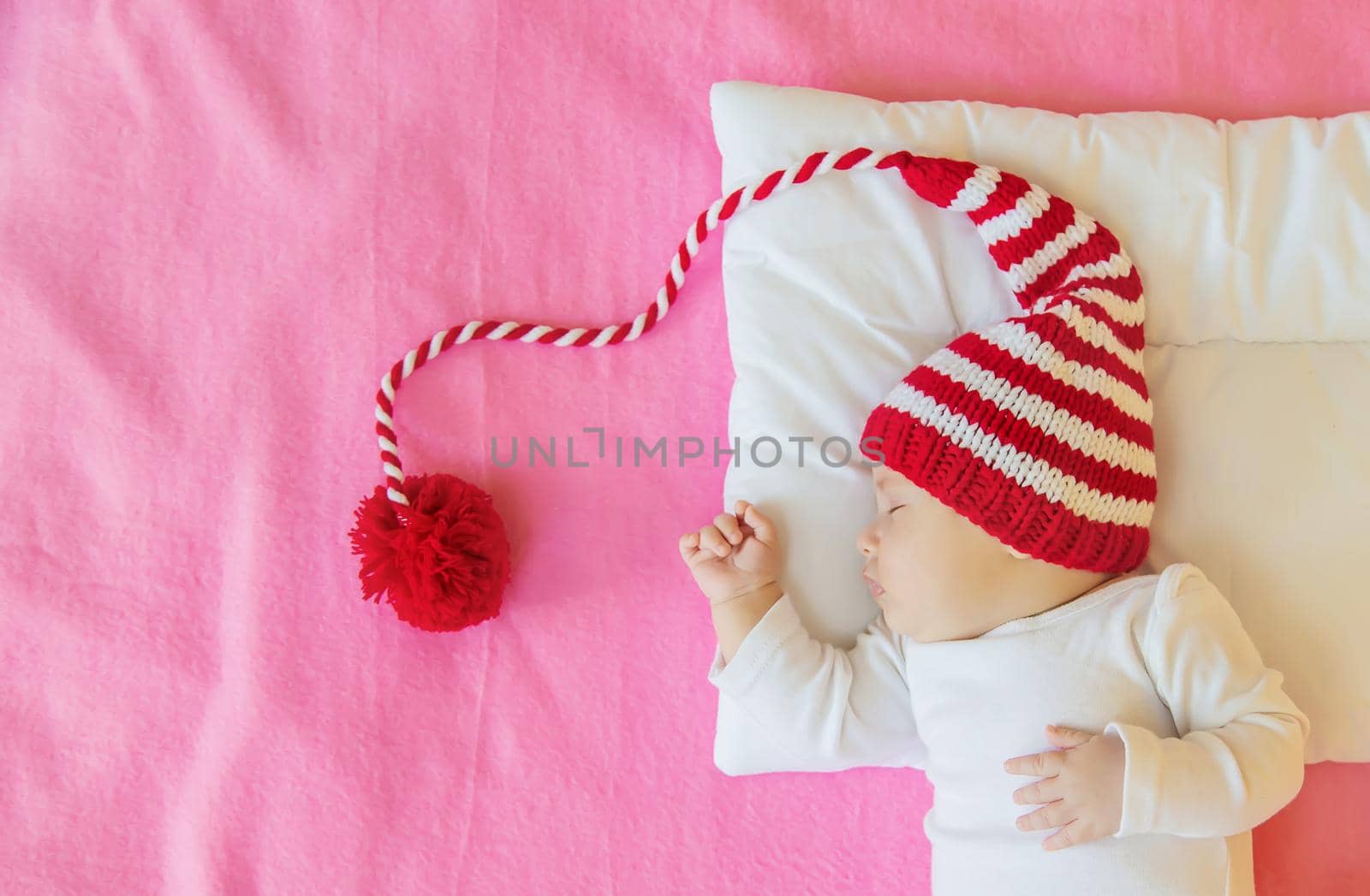Baby sleeps in a Santa hat. Selective focus. People. Merry Christmas and Happy New Year, Holidays greeting card background. Selective focus.