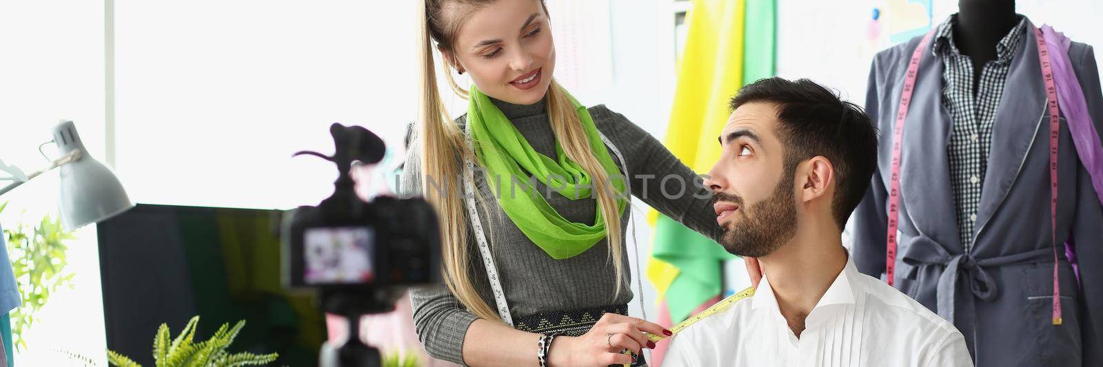 Portrait of woman designer measuring shoulder of her colleague on camera. Dressmaker teach followers how sew clothes. Business, blogger, creative concept