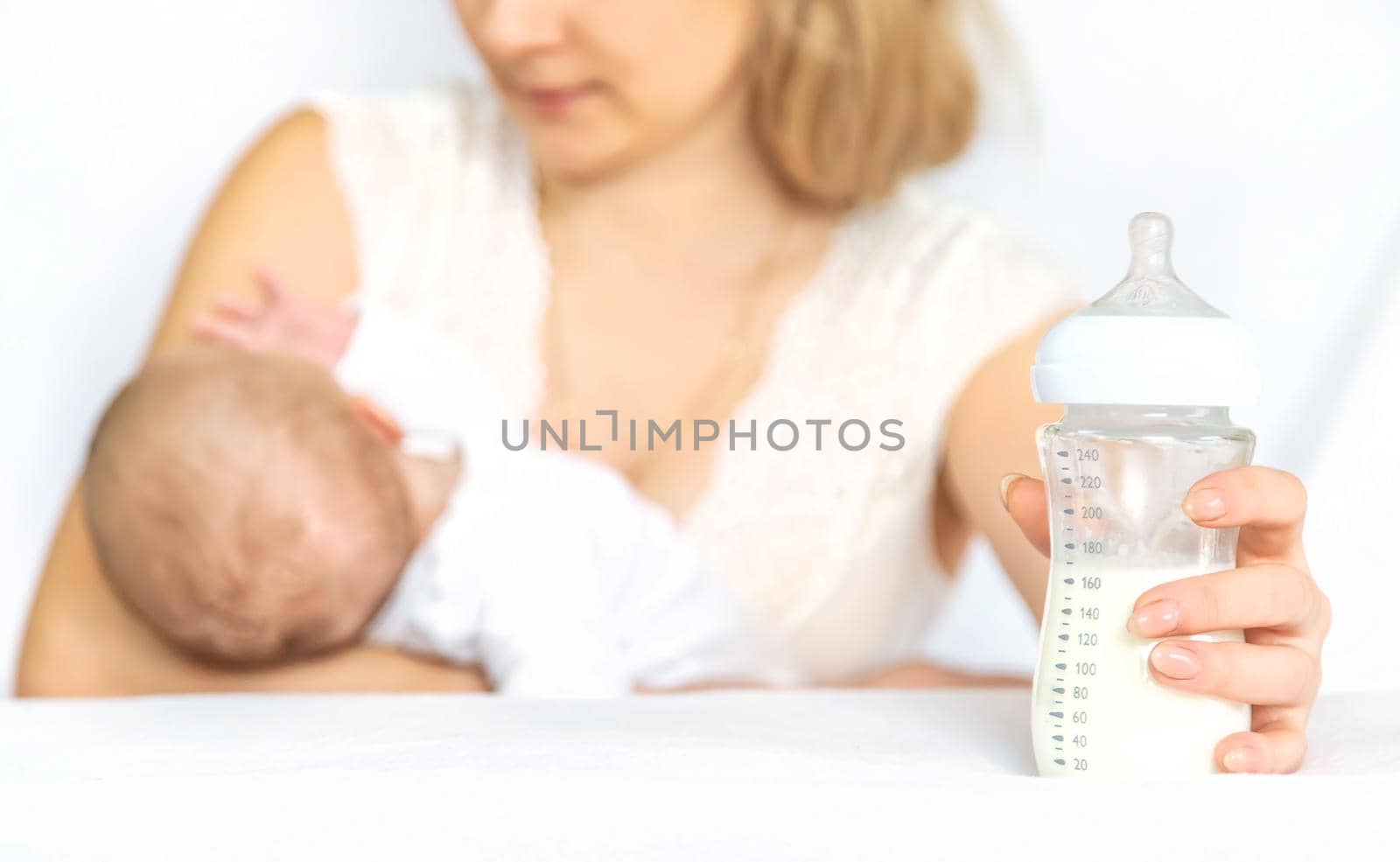 Mother feeds the baby from a bottle. Selective focus. People.