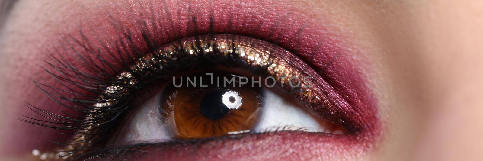 Close-up of beautiful makeup on young woman brown eye, model for makeup tutorial. New year decor on face, looking up. Art, facial beauty, wellness concept