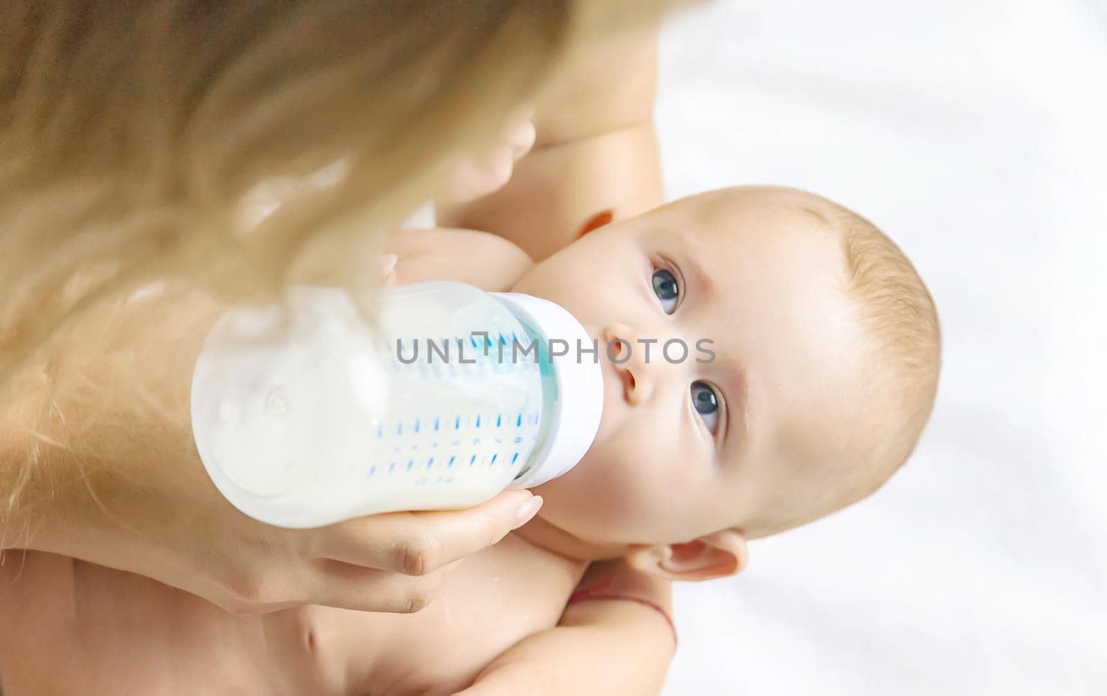 Mom feeds the baby with a bottle. Selective focus. People.