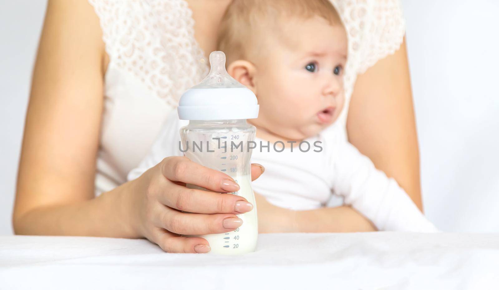 Mother feeds the baby from a bottle. Selective focus. People.