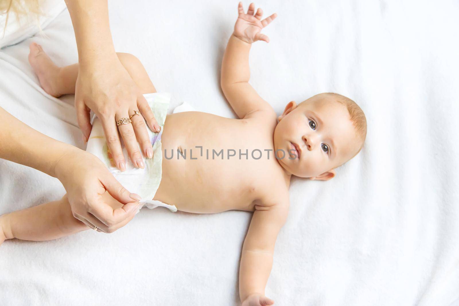 The mother changes the baby's diaper. Selective focus. People.