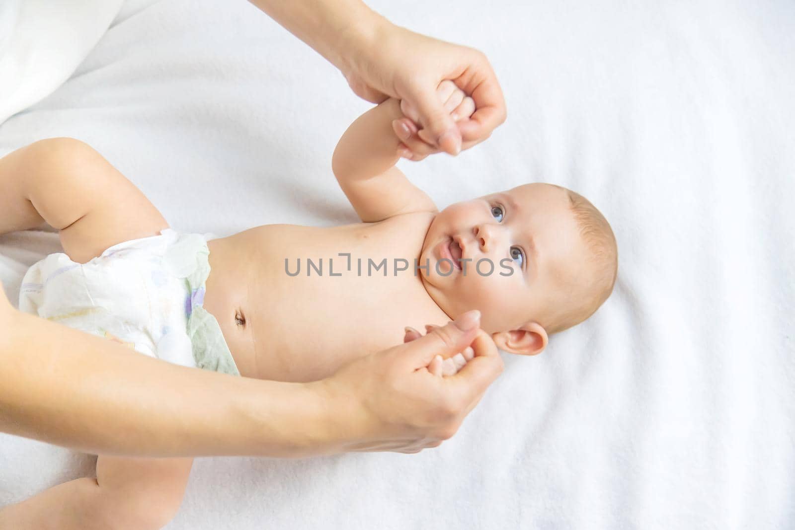 Mother massage baby on the bed. Selective focus. people.