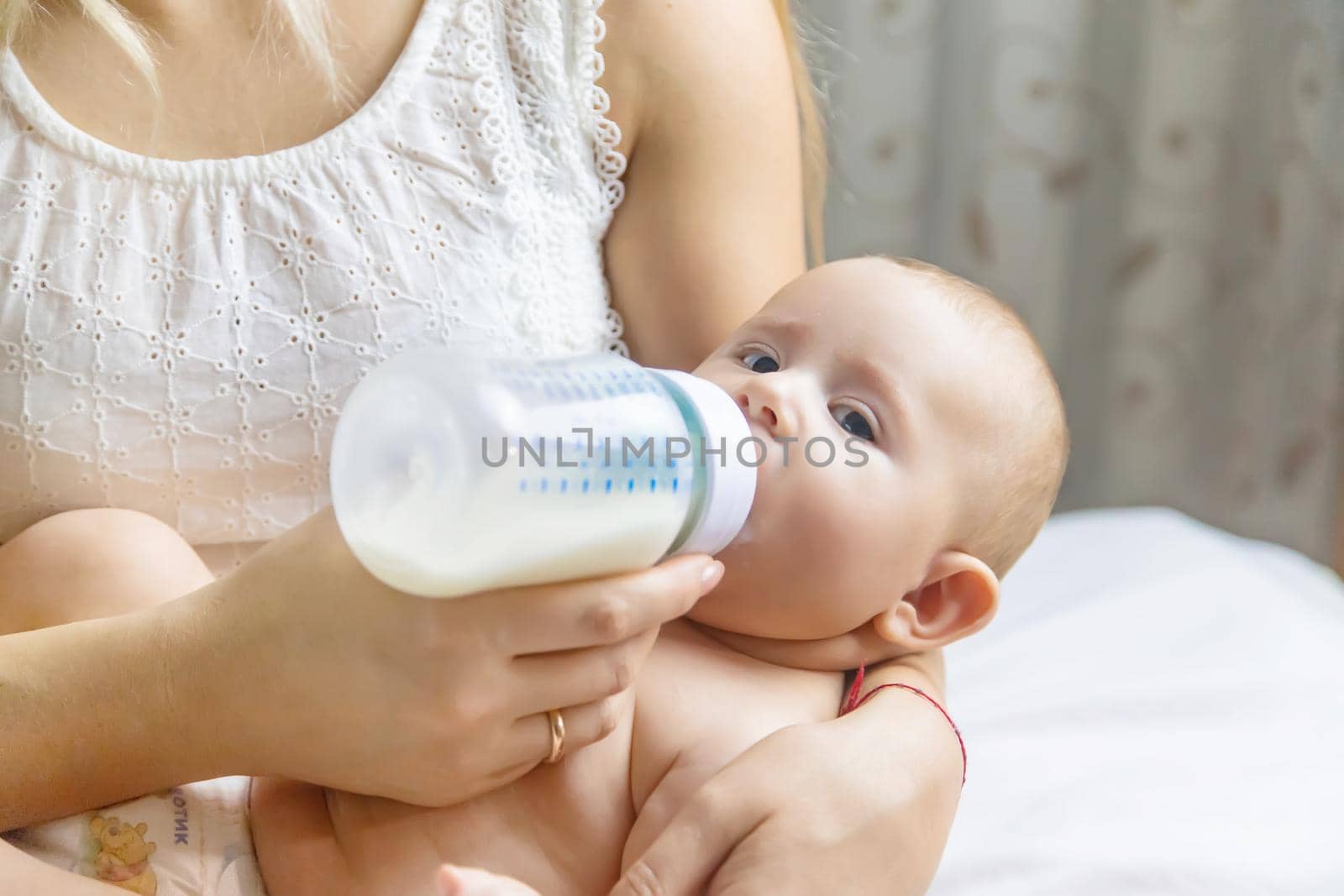 Mom feeds the baby with a bottle. Selective focus. by yanadjana