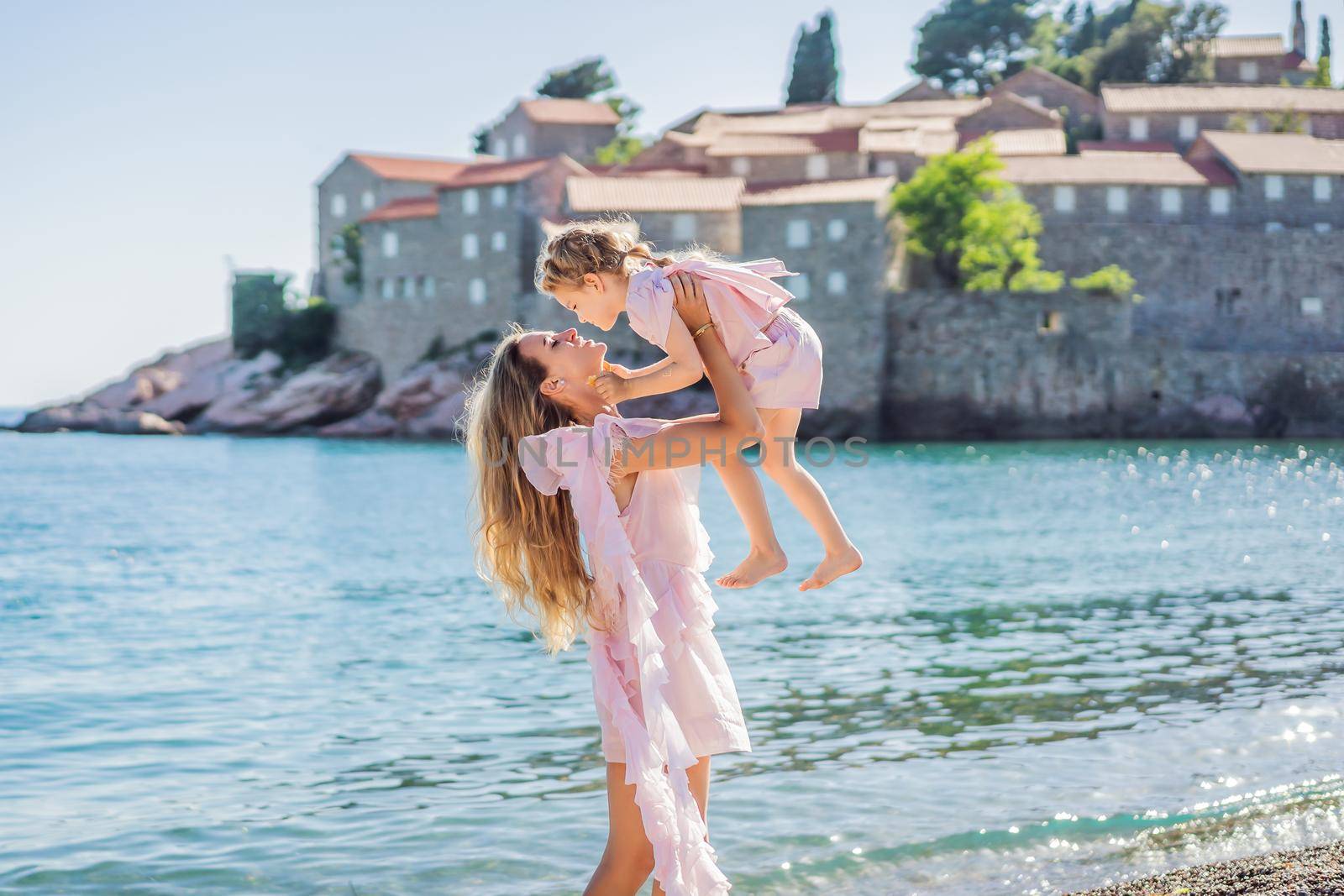 Mother and daughter tourists on background of beautiful view St. Stephen island, Sveti Stefan on the Budva Riviera, Budva, Montenegro. Travel to Montenegro concept.