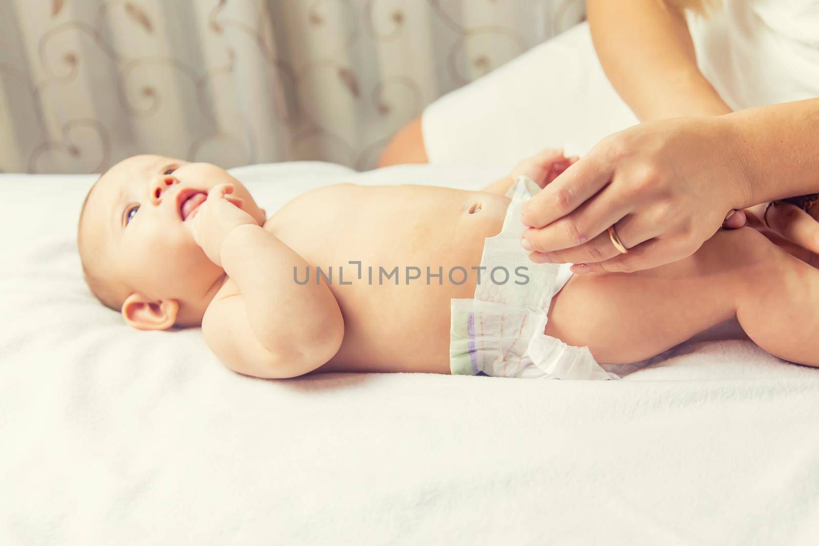 The mother changes the baby's diaper. Selective focus. People.