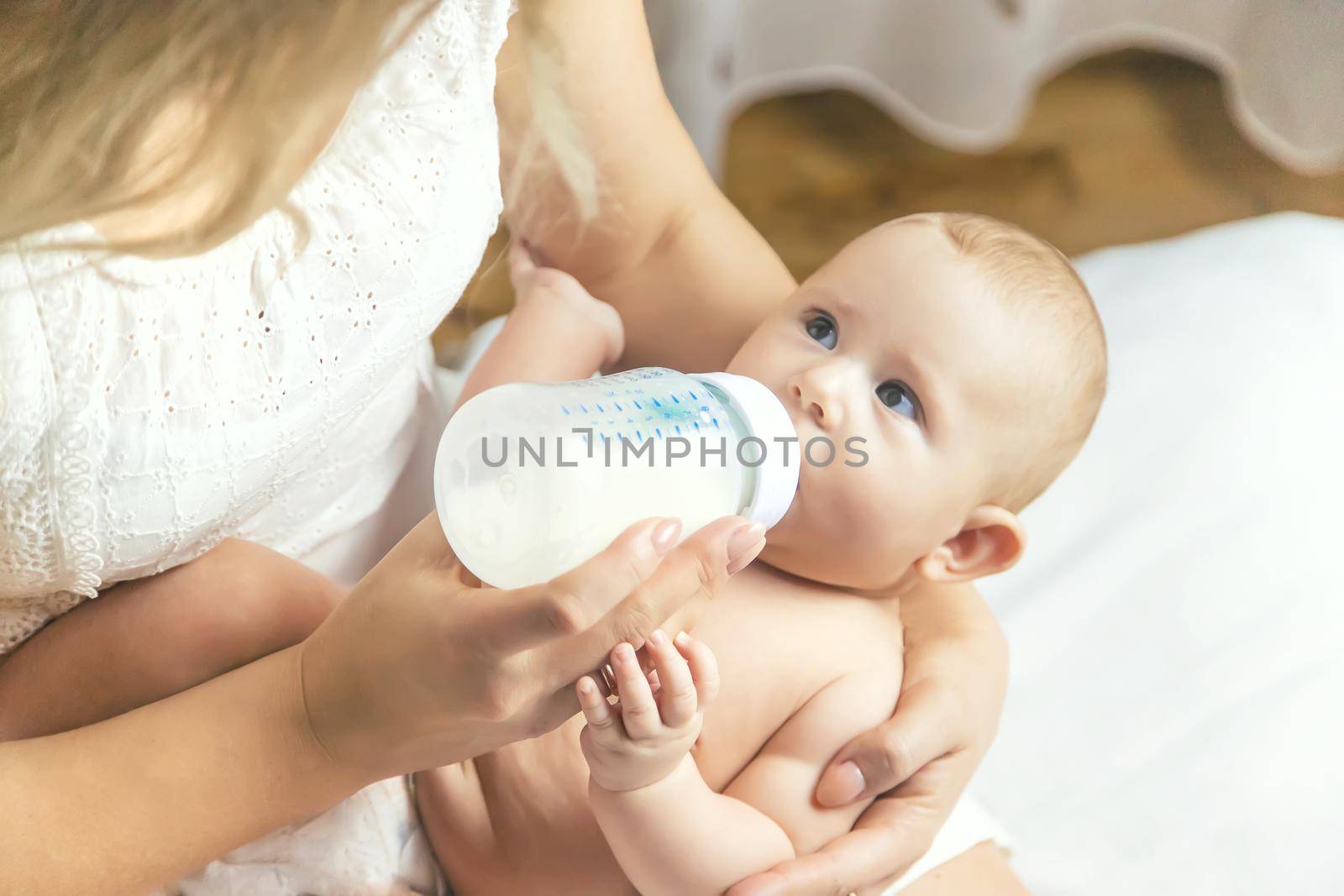 Mom feeds the baby with a bottle. Selective focus. People.