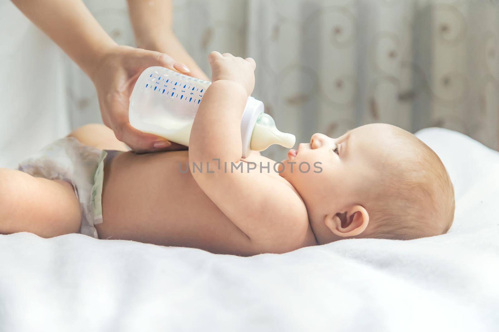 Mom feeds the baby with a bottle. Selective focus. People.