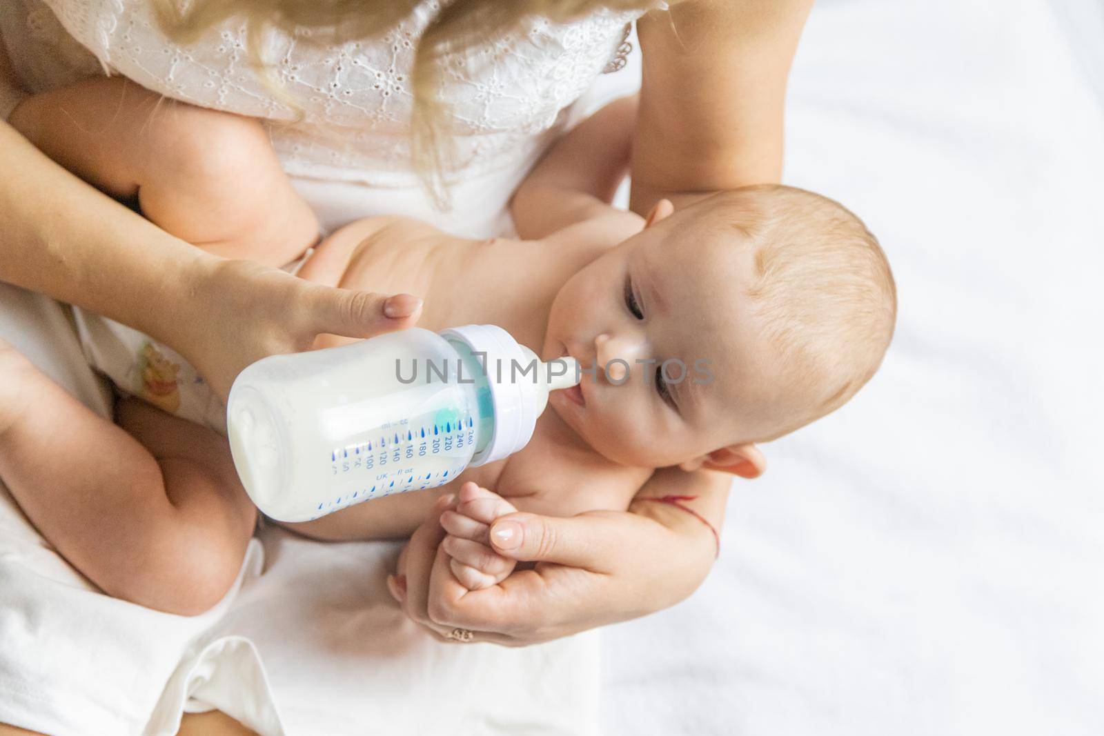 Mom feeds the baby with a bottle. Selective focus. People.