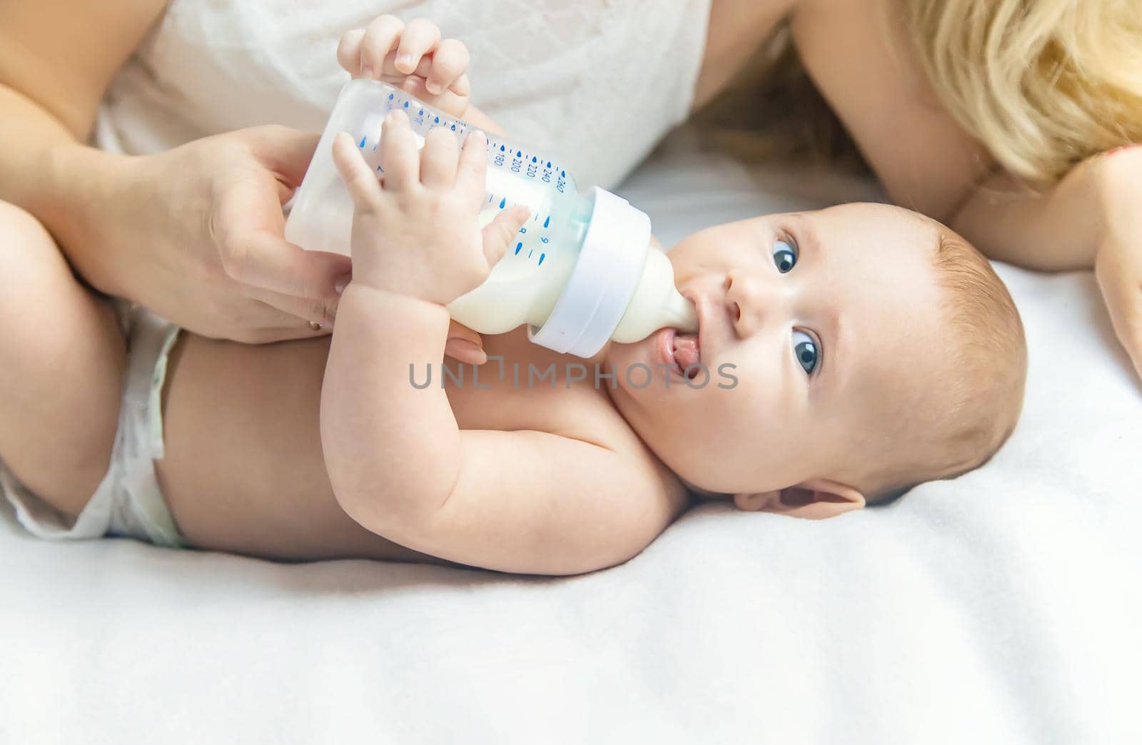 Mom feeds the baby with a bottle. Selective focus. People.