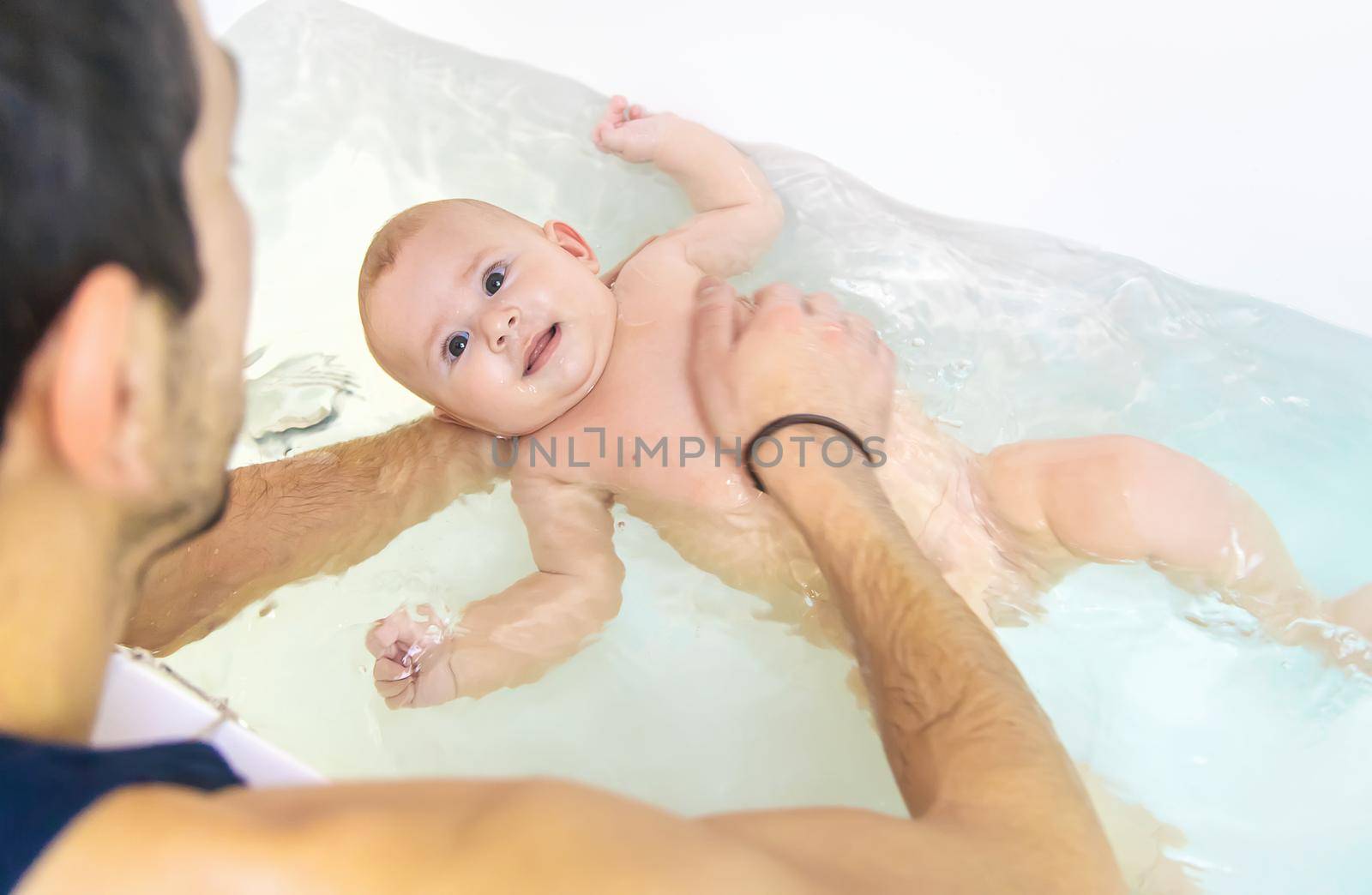The father bathes the little baby. Selective focus. Copy space.