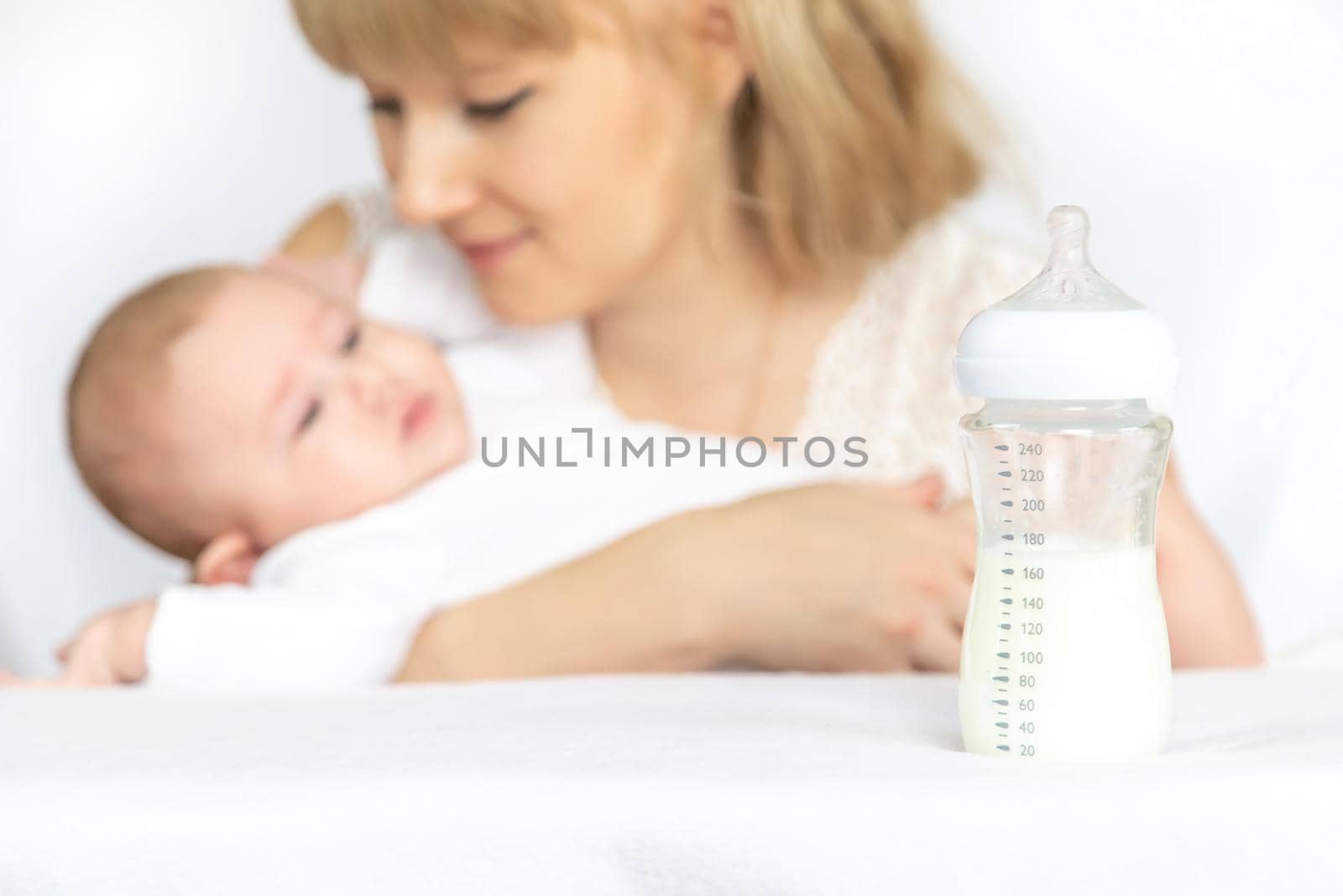 Mother feeds the baby from a bottle. Selective focus. People.