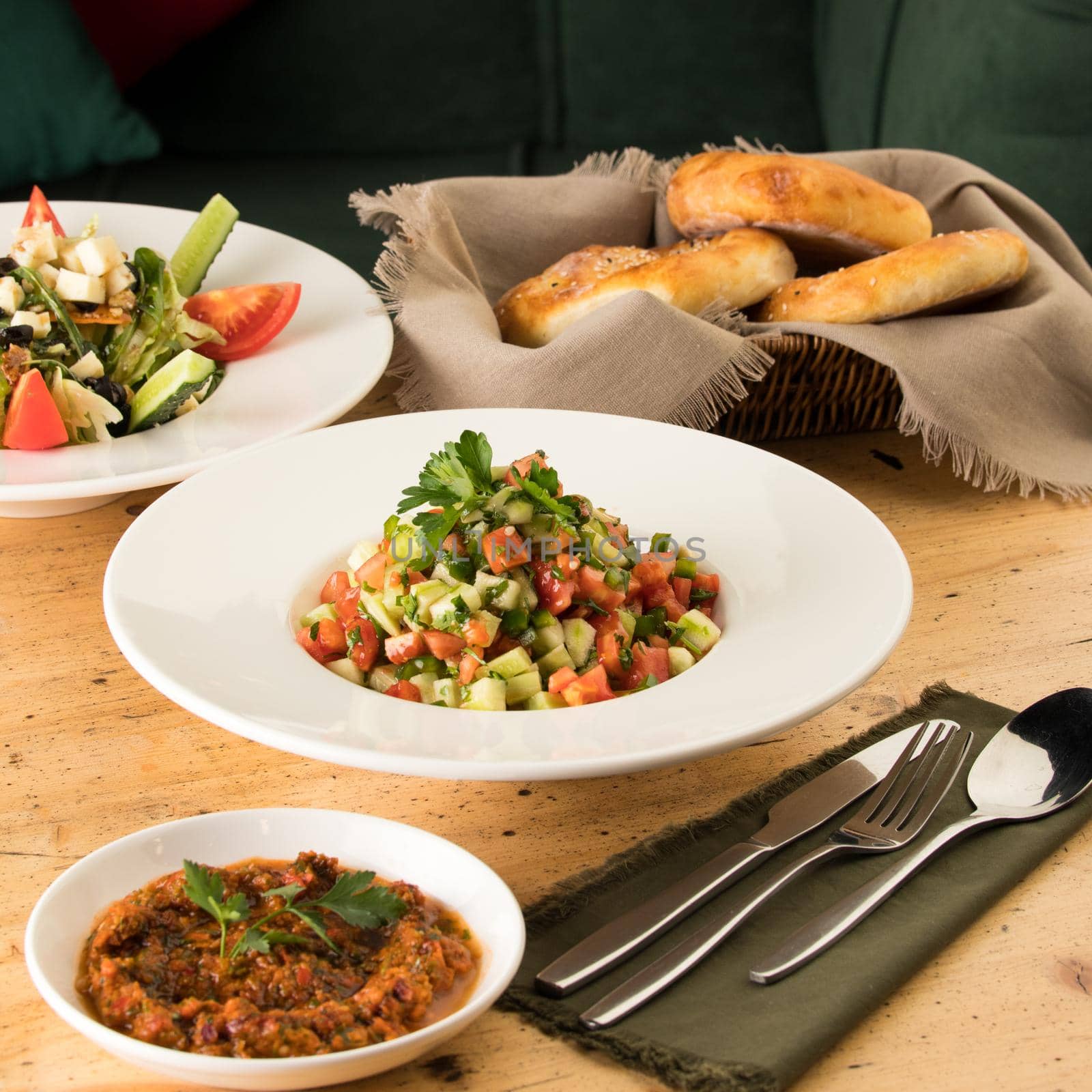 A close up shot of salads and appetizers near basket of breads