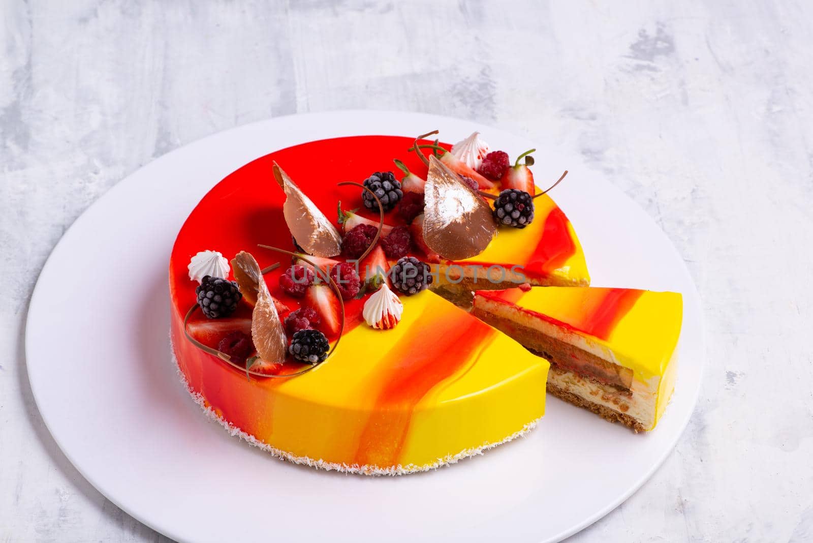 A closeup shot of a tasty cake topped with candies and fresh fruits