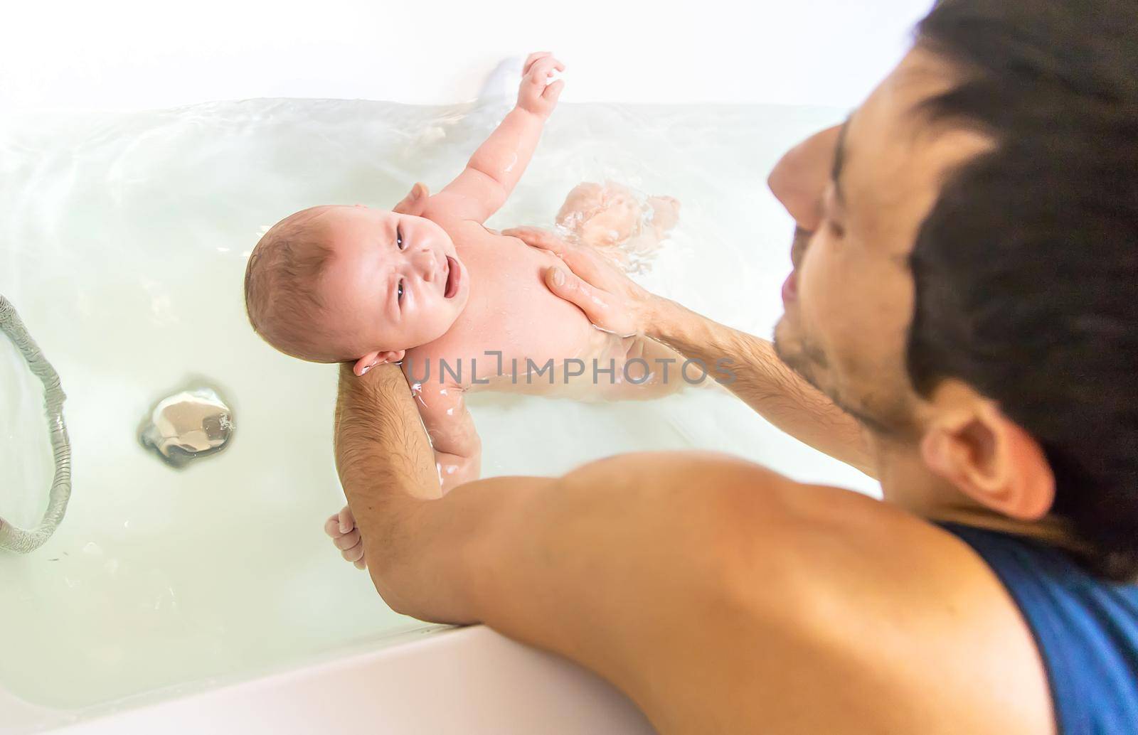 Little baby crying is afraid to swim in the bathroom. Selective focus. People.