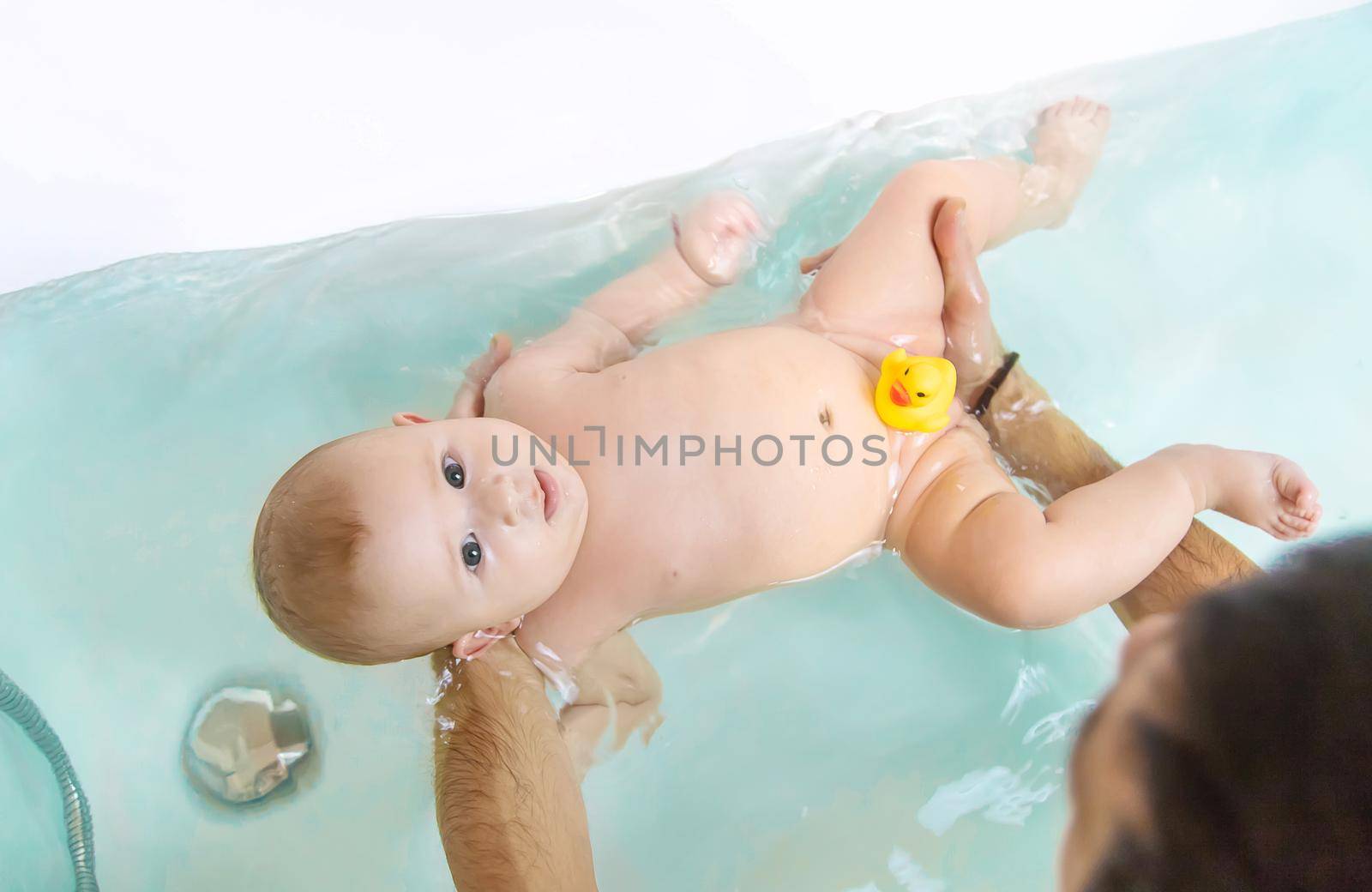 The father bathes the little baby. Selective focus. Copy space.