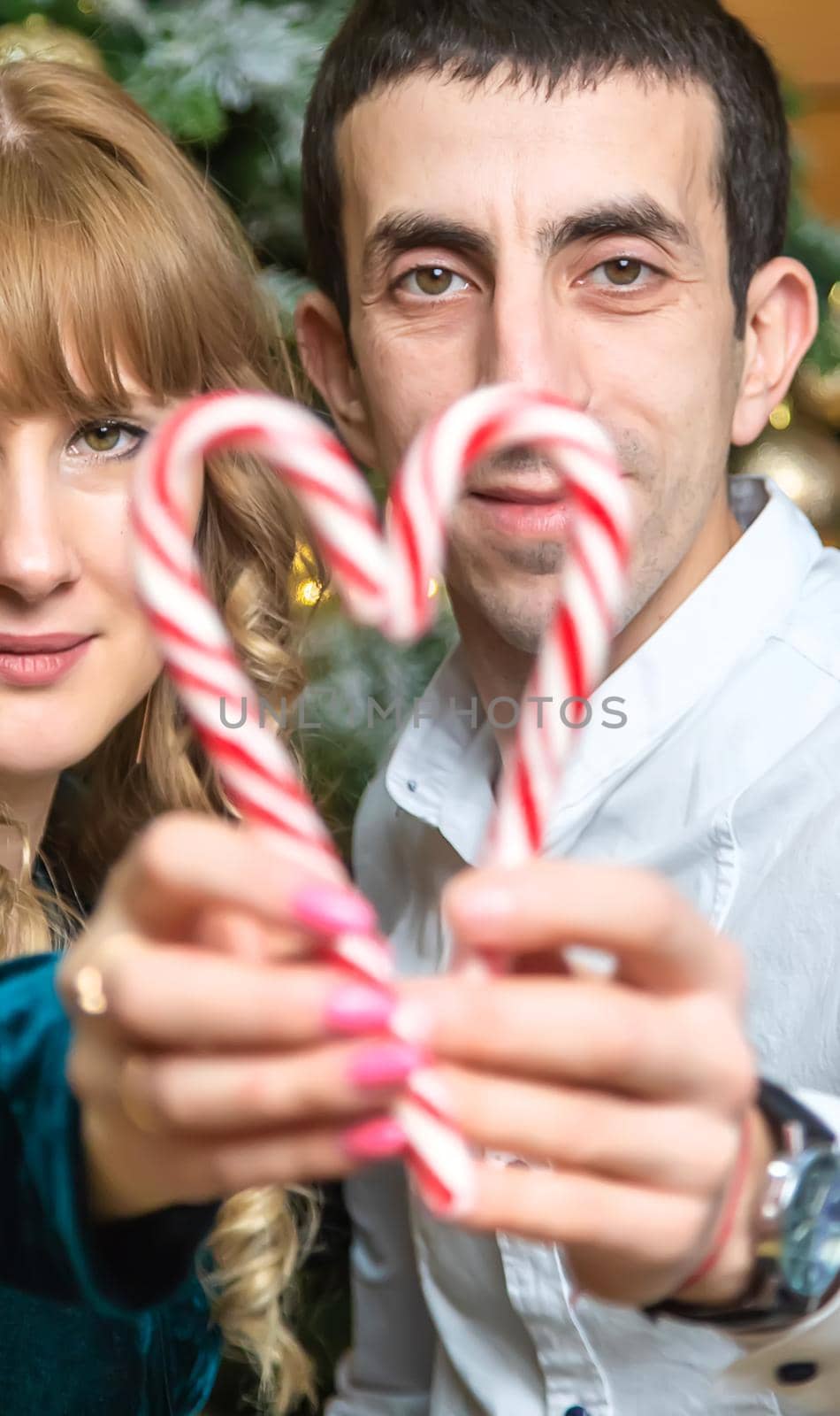 Christmas lollipops in the hands of a man and a woman. Selective focus. Holiday.