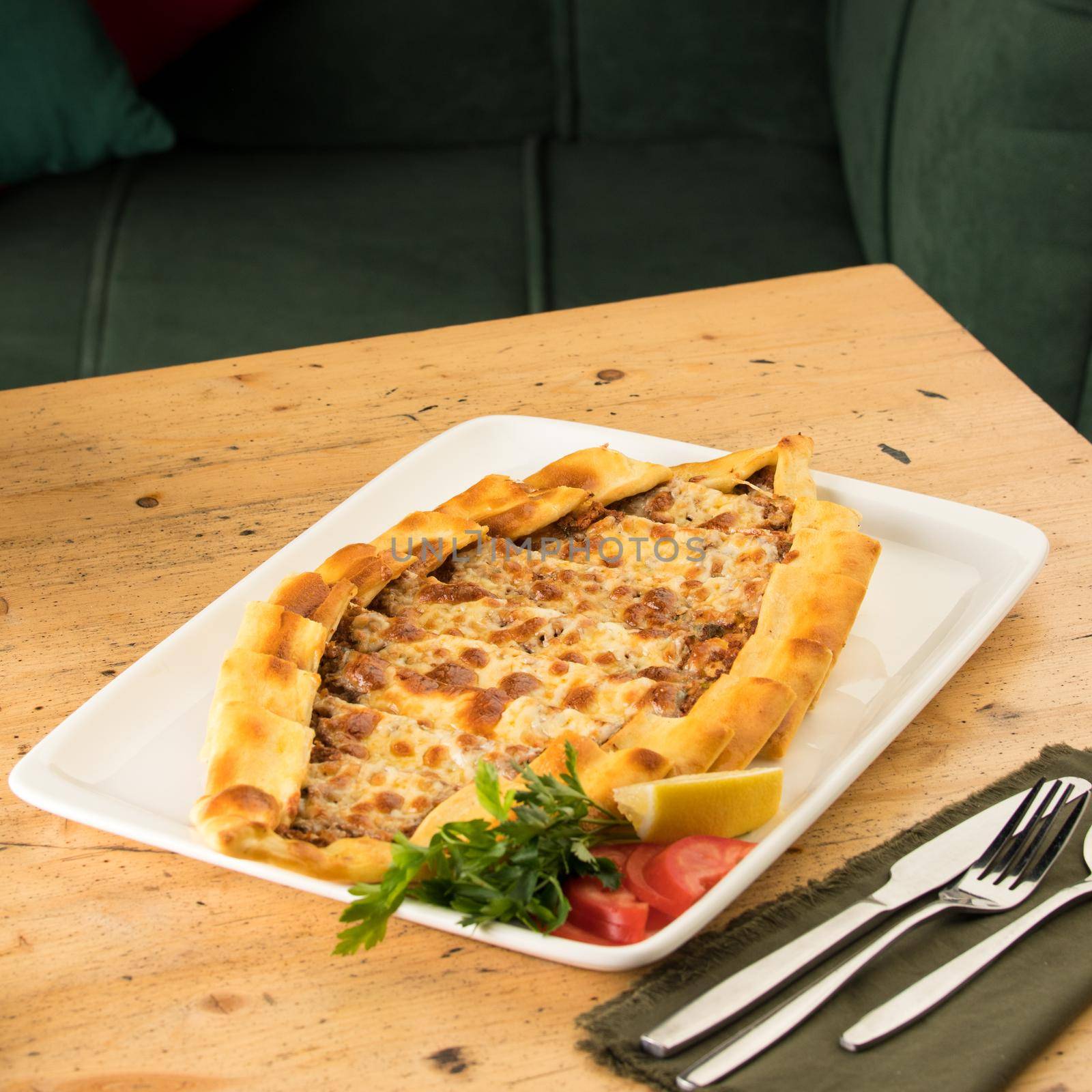 A traditional Turkish baked pide in a white plate on a wooden table