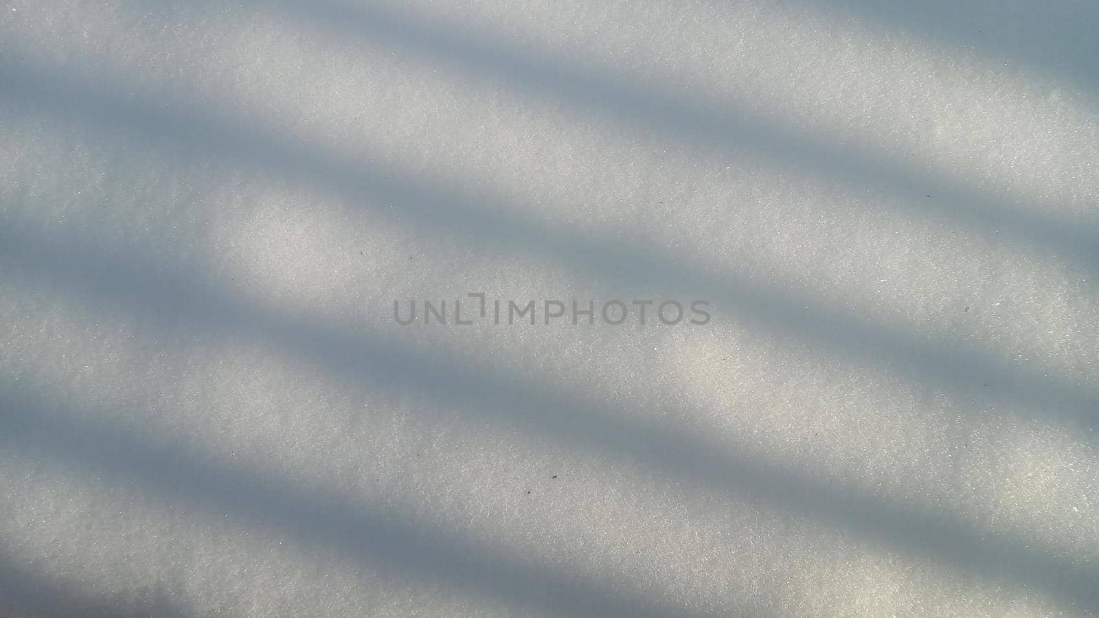 Background with natural snow texture, close-up from above. Shadow in the form of straight lines on a snowy surface, abstract background.