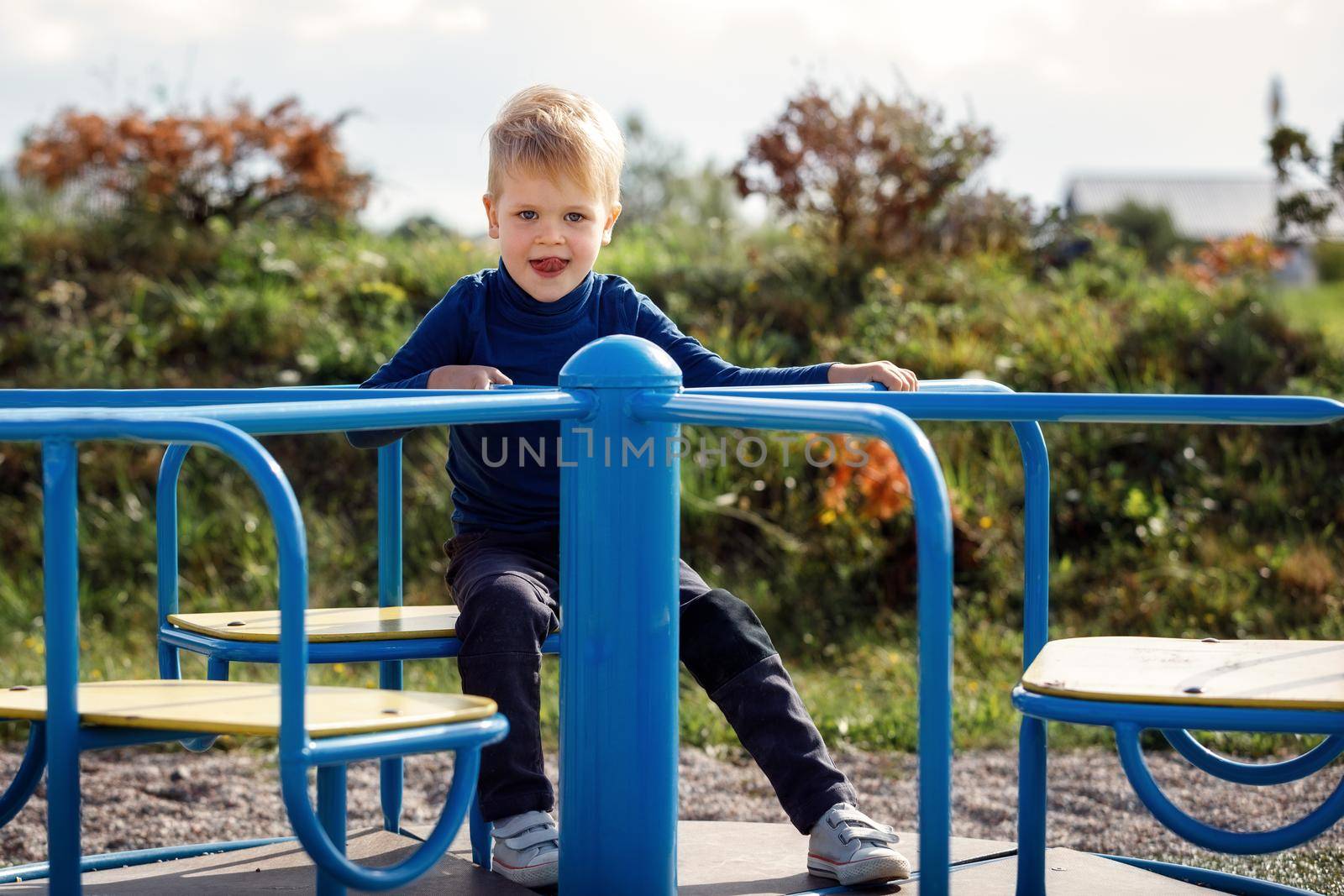 Portrait of cheerful boy sitting on merry-go-round. Concept of child development, sports and education.