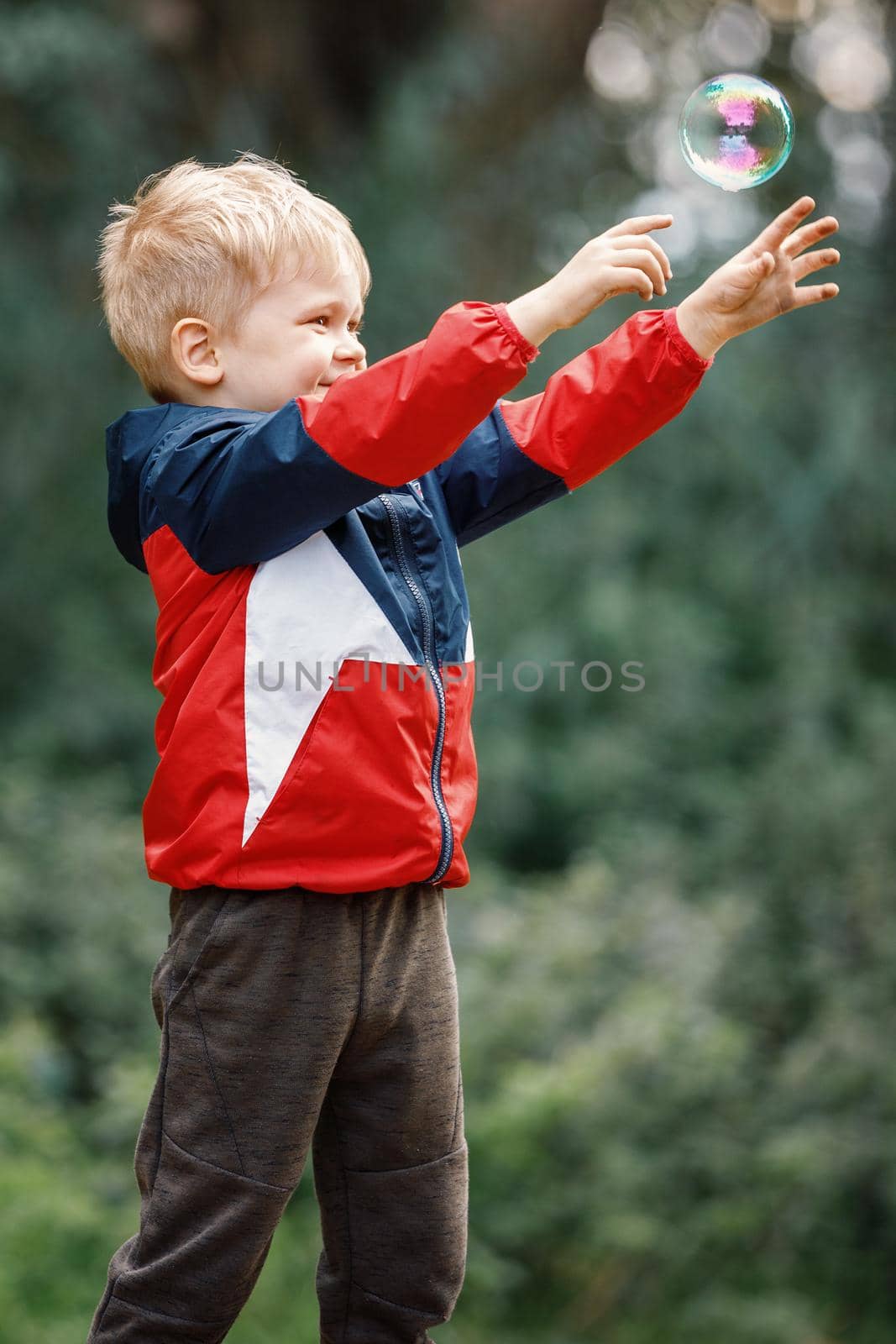 Very happy kid trying to catch soap bubble.