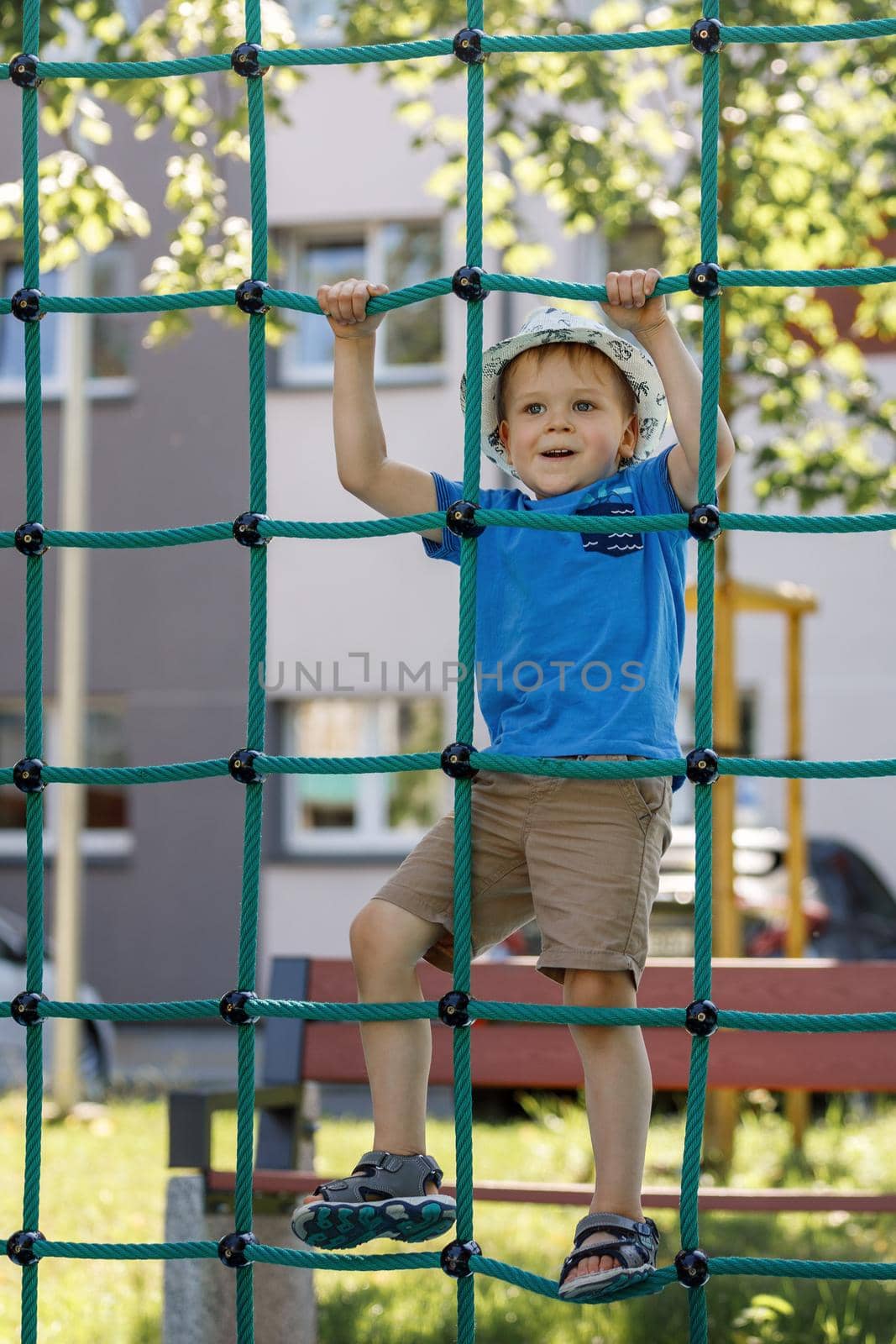 Child at playground. Little boy on a playground climbing net tower. Outdoor play space on Polyester Twisted Rope. Playground Climbing Rope Tower