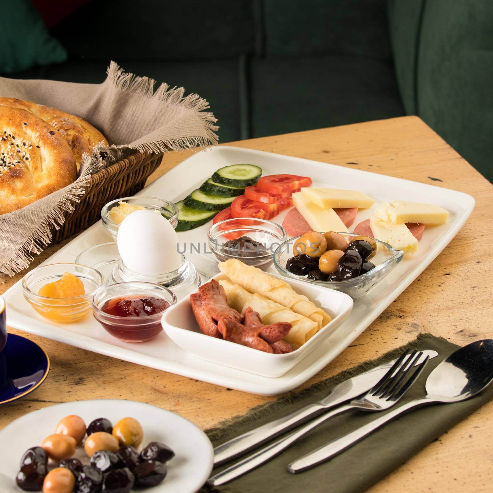 A breakfast plate and a basket of bread on a wooden table