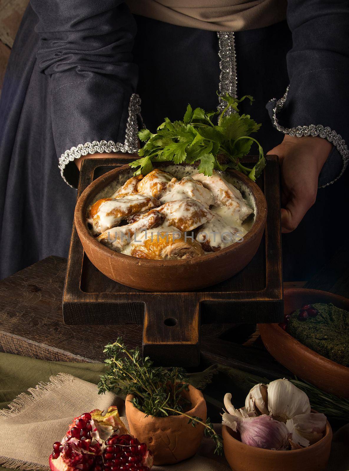 A vertical shot of a waitress presenting a chicken covered in a creamy sauce