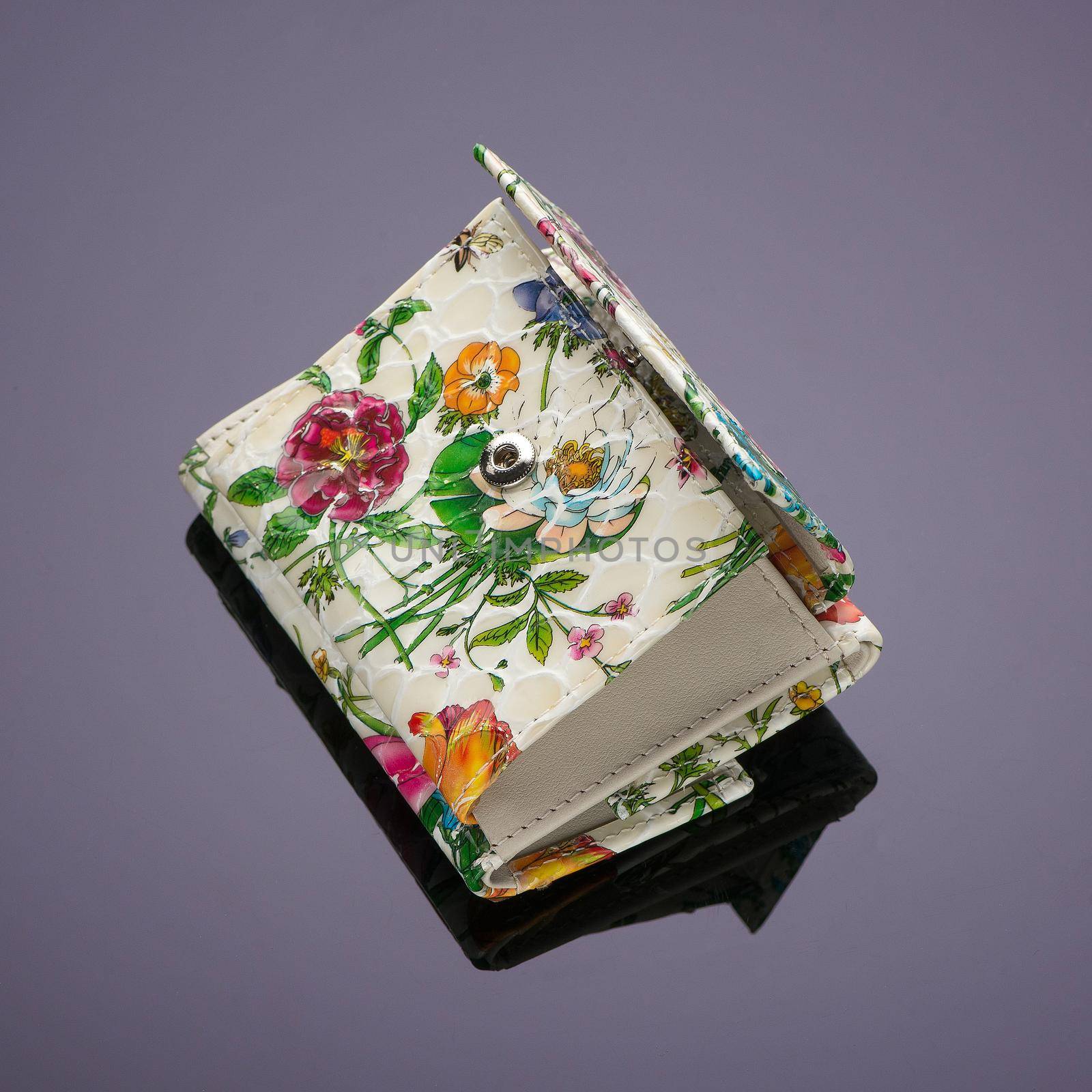 A close-up shot of a floral money purse placed on a reflecting surface.