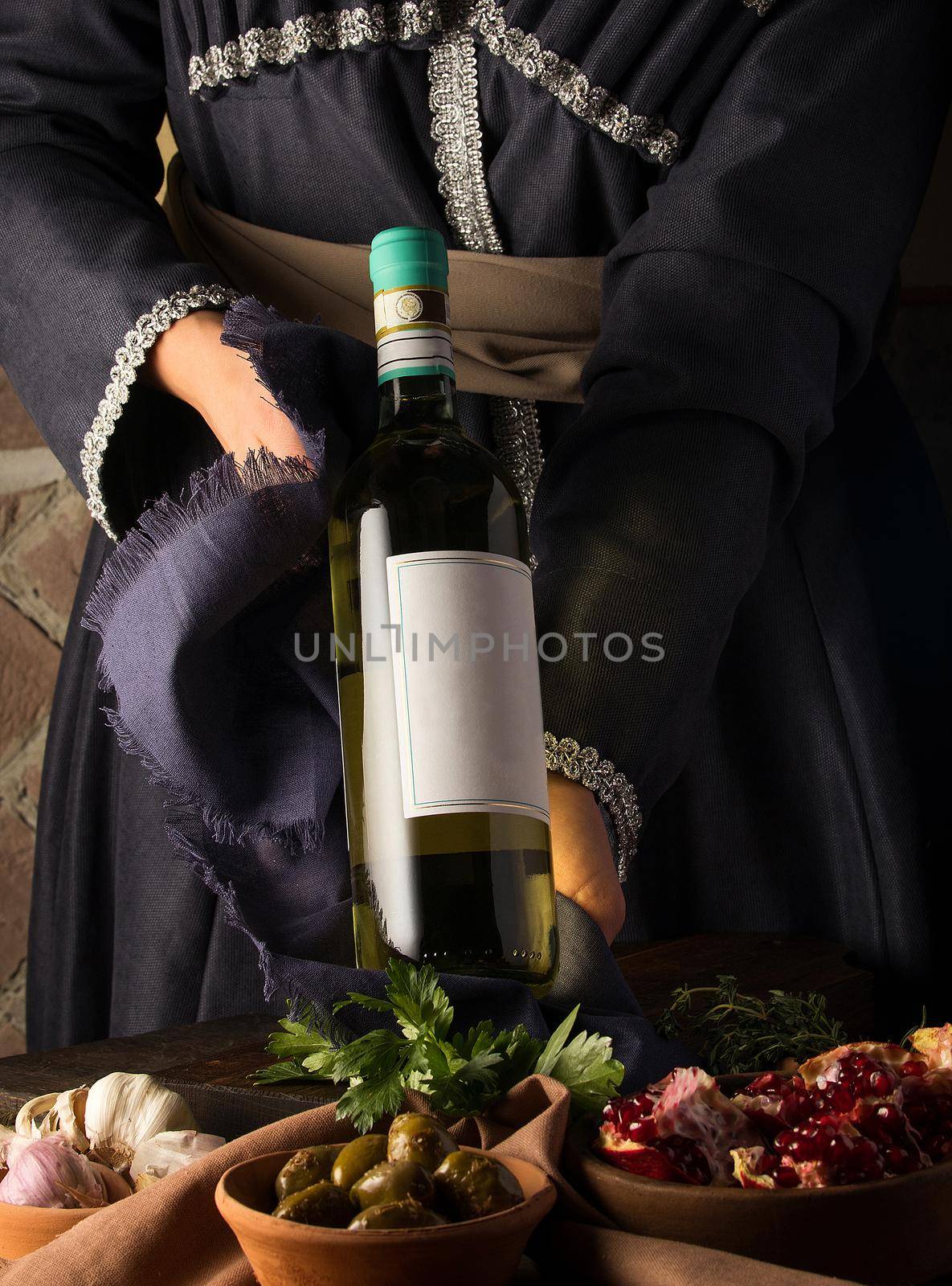 Vertical shot of a person in a traditional costume showing a wine bottle by A_Karim