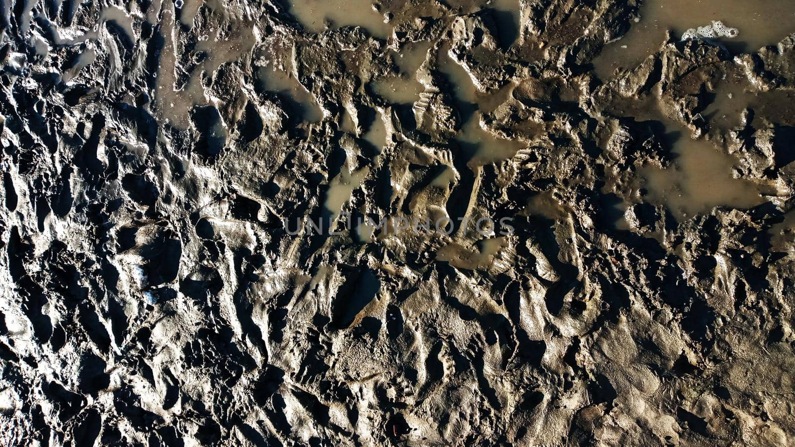 Iiquid mud with footprints. Footprint or imprint shoe in the mud.Mud texture or wet brown soil as natural organic clay and geological sediment mixture as in roughing it in a dirty muddy country ground after the rain or rainy.