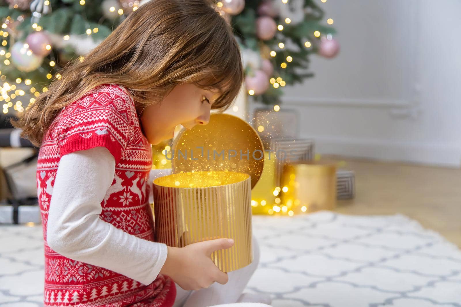 Child opens gifts under the Christmas tree. Selective focus. Holiday.