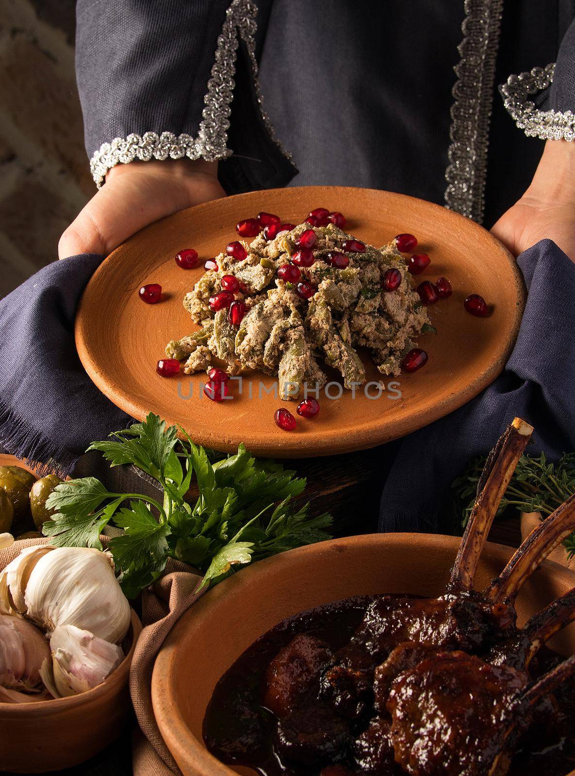 Vertical shot of a waitress presenting a kuchmachi and tomahawk steak in the background by A_Karim