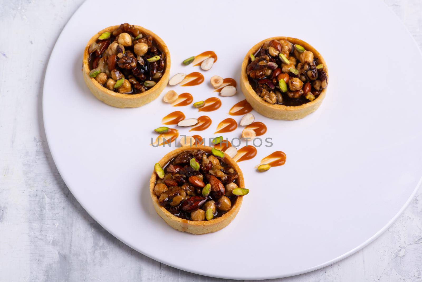 The appetizing tartlets stuffed with hazelnuts walnuts covered with a layer of liquid caramel