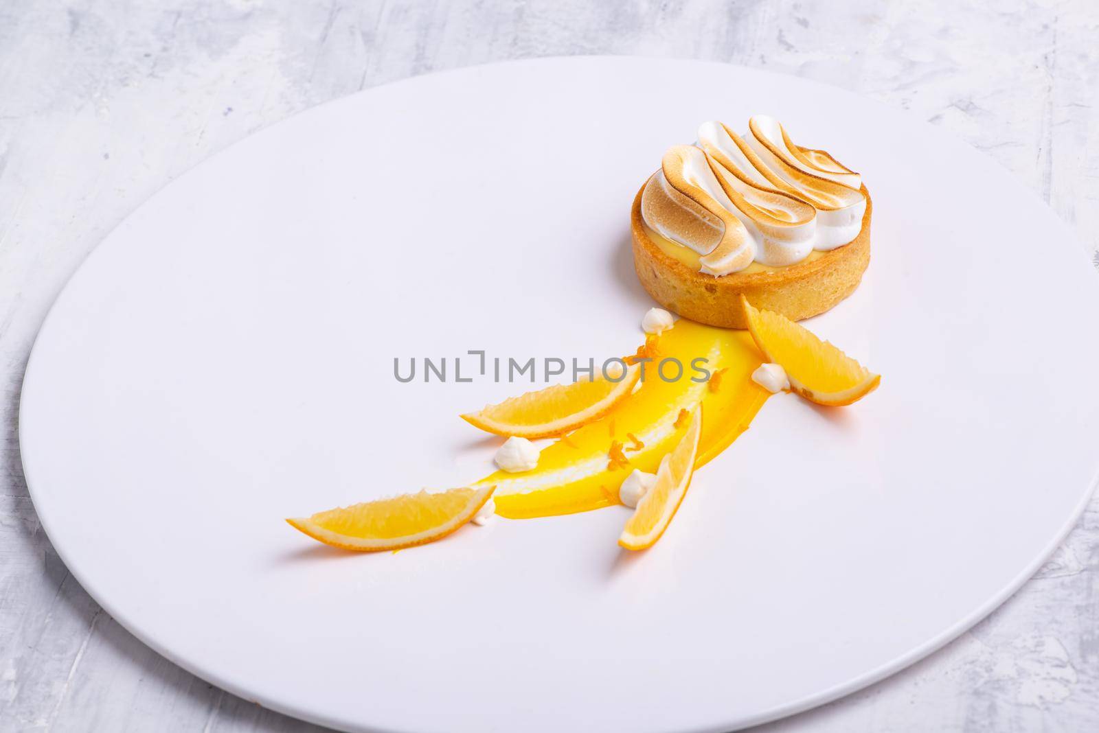 The appetizing lemon tartlets with meringue served on a white plate