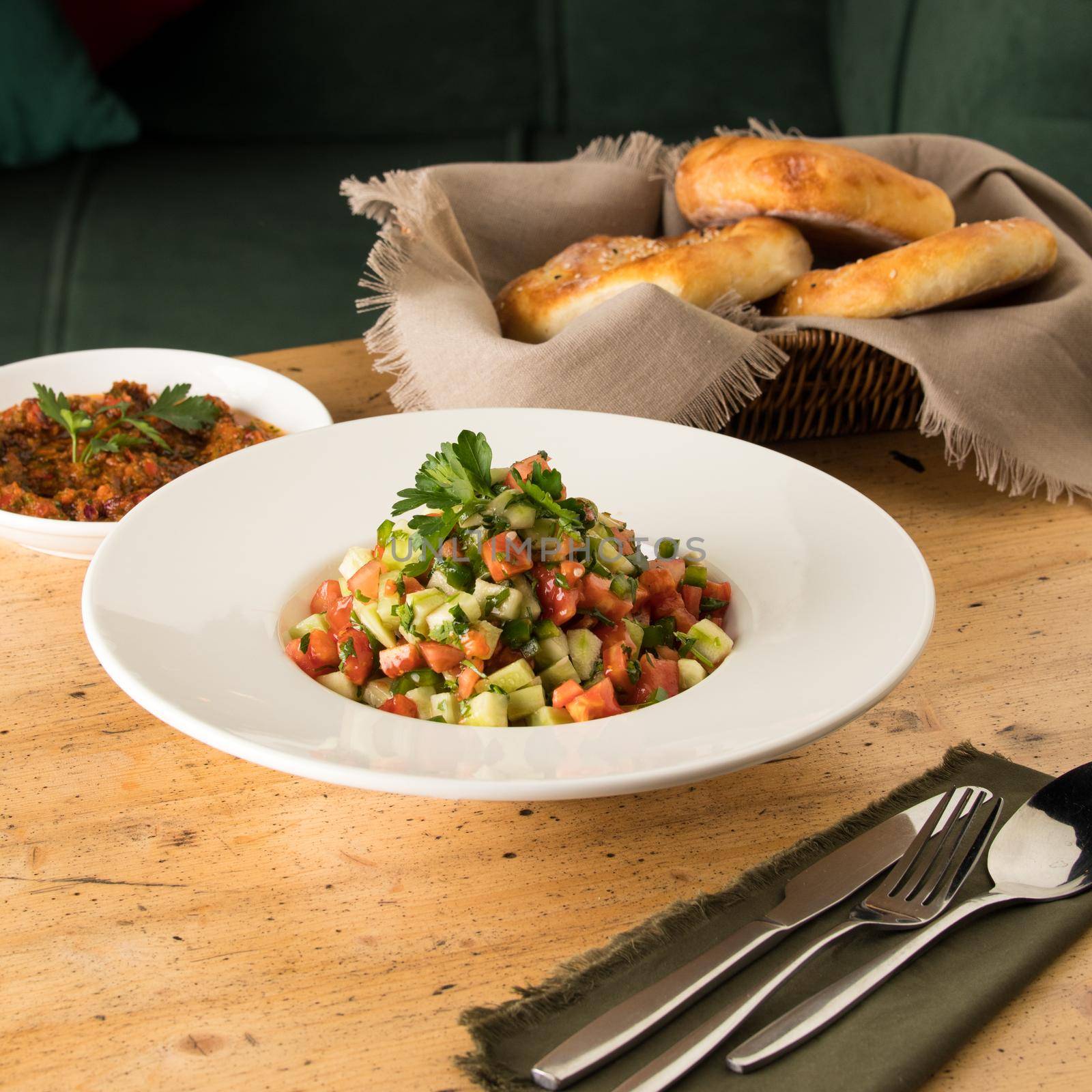 Close up shot of salads and appetizers near basket of breads by A_Karim