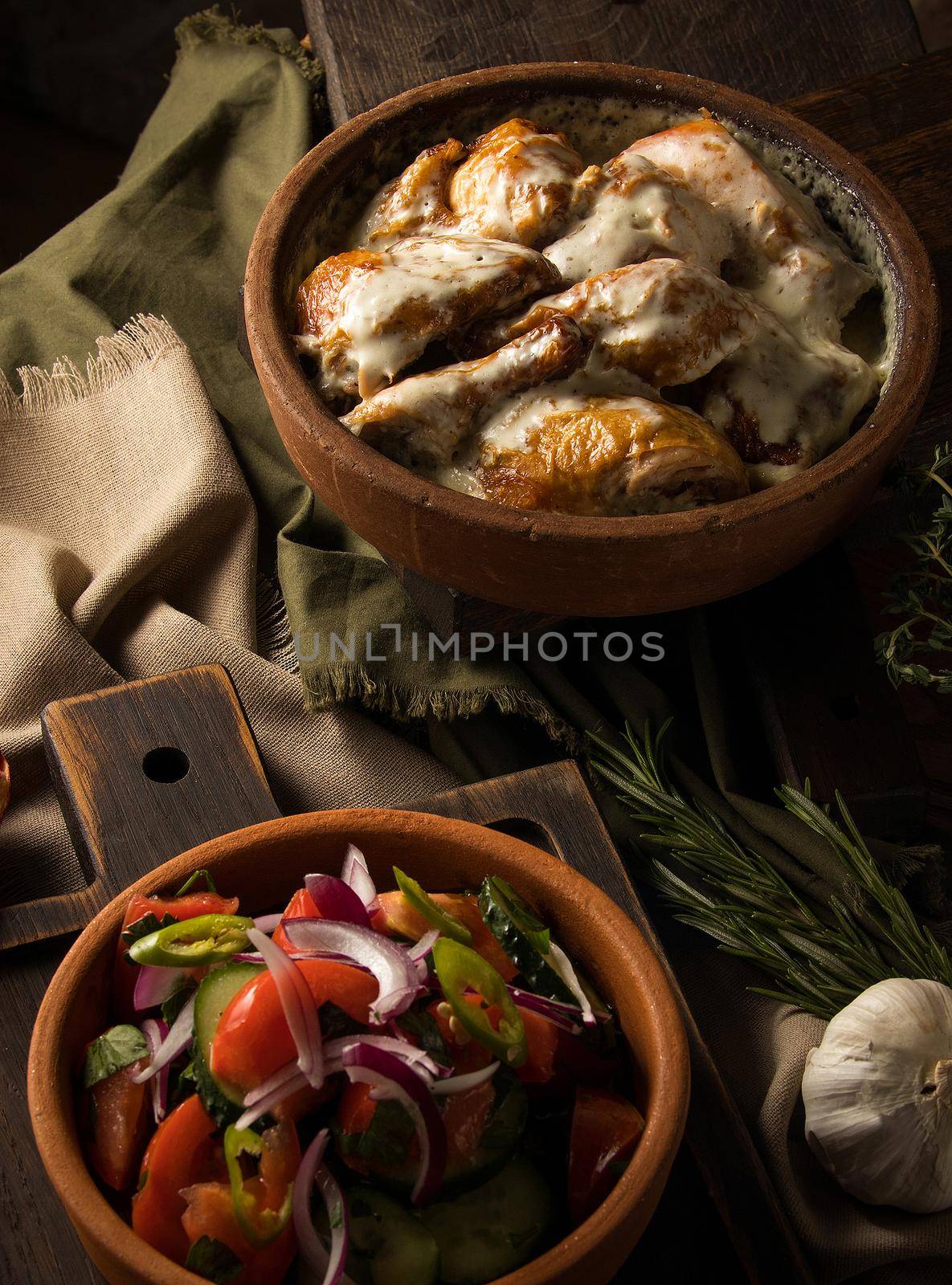 A vertical shot of a chicken covered in creamy sauce and eggplant salad