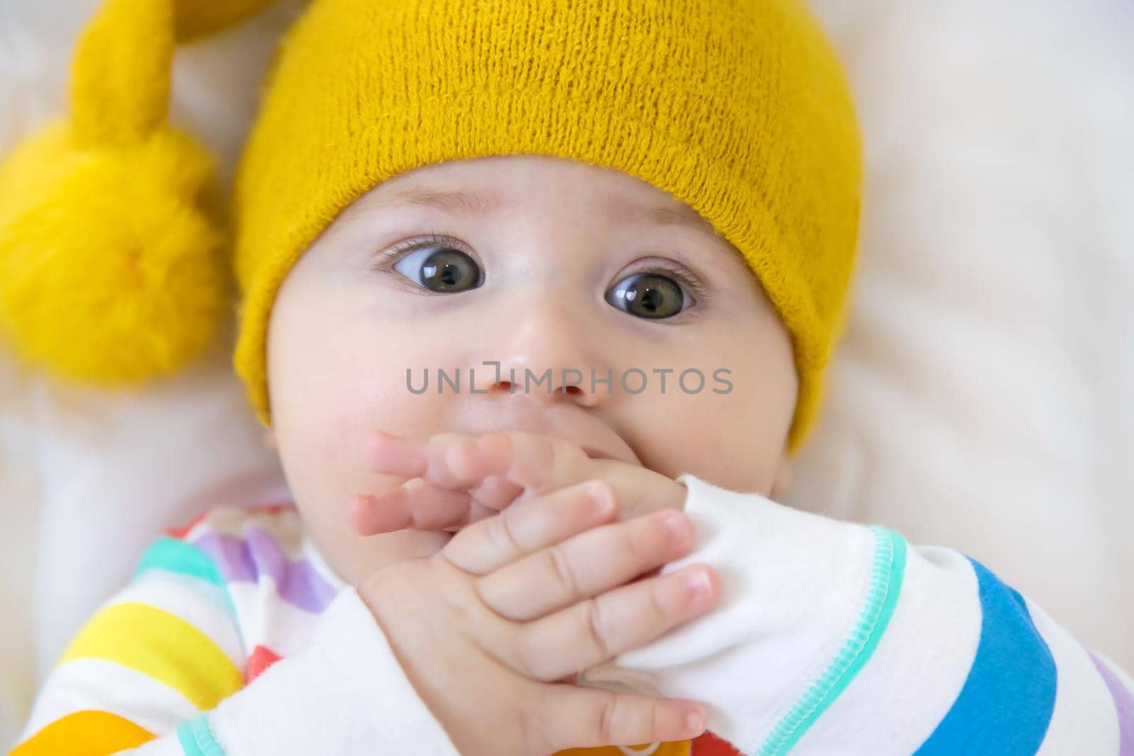Baby puts his hands in his mouth. Selective focus. People.