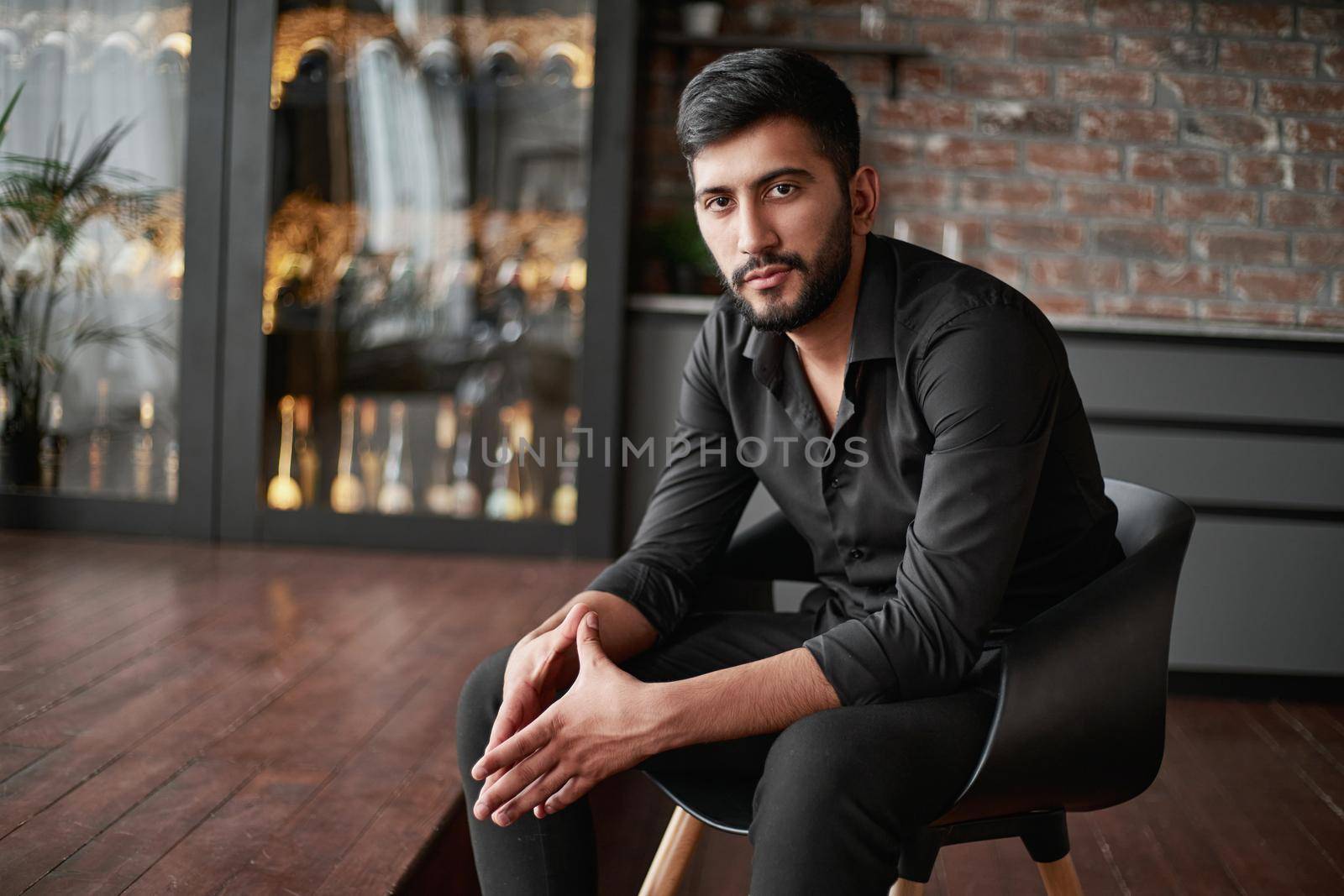 portrait of a business owner sitting in his wine shop.