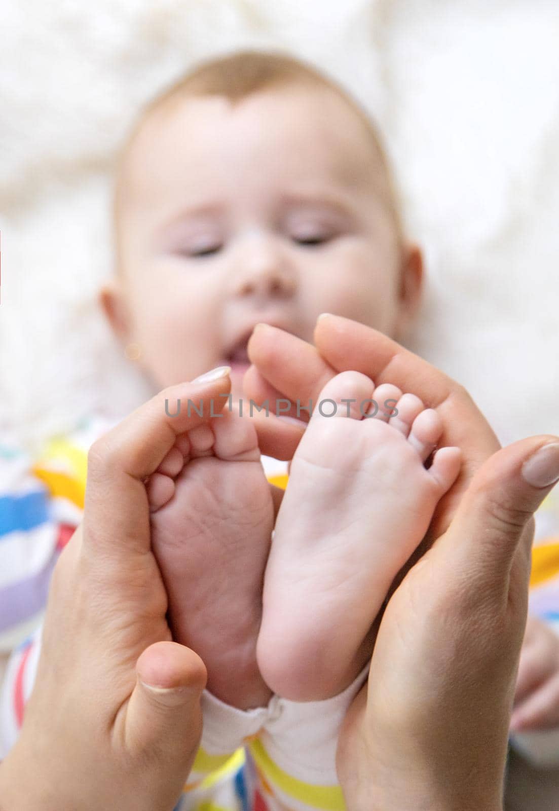 The mother holds the legs of her baby. Selective focus. Child.