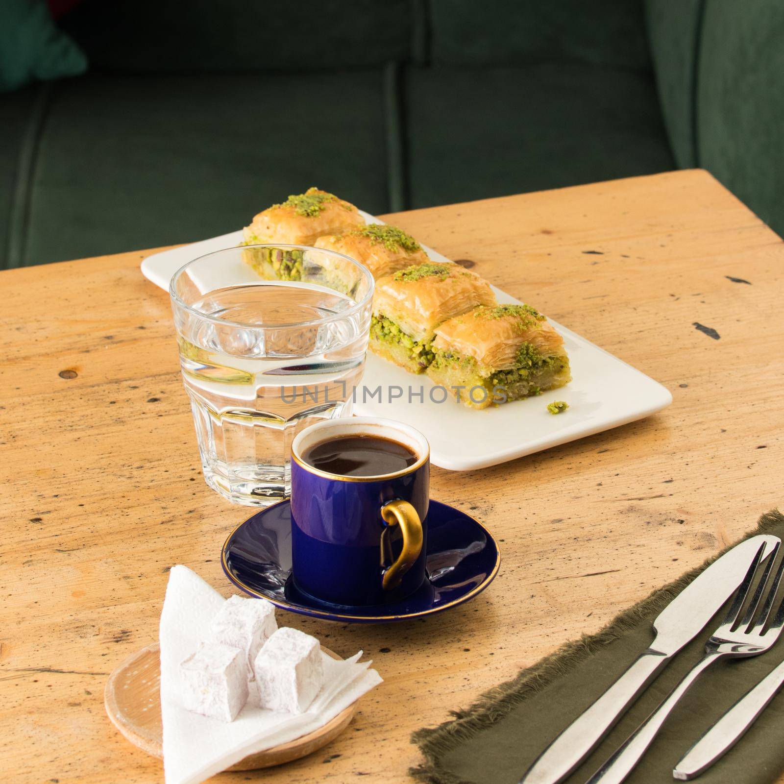 A cup of coffee near glass of water and baklava