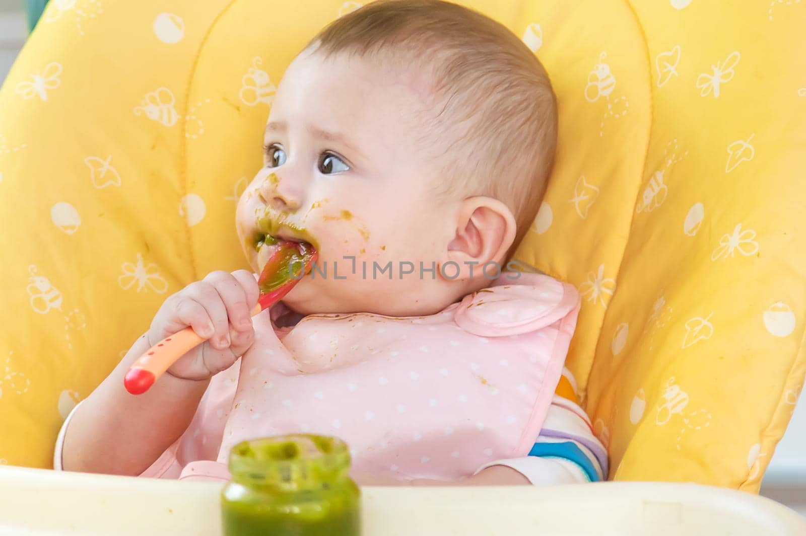 Little baby is eating broccoli vegetable puree. Selective focus. People.