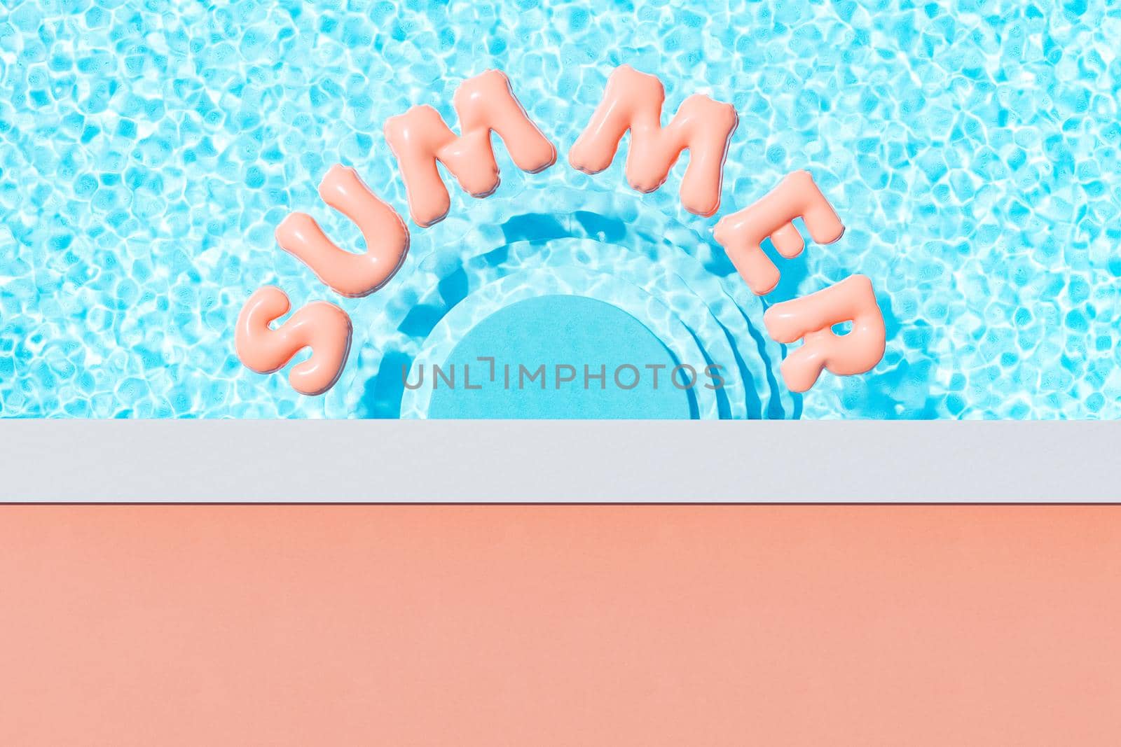pool with floating pink inflatable letters in sunlight by asolano