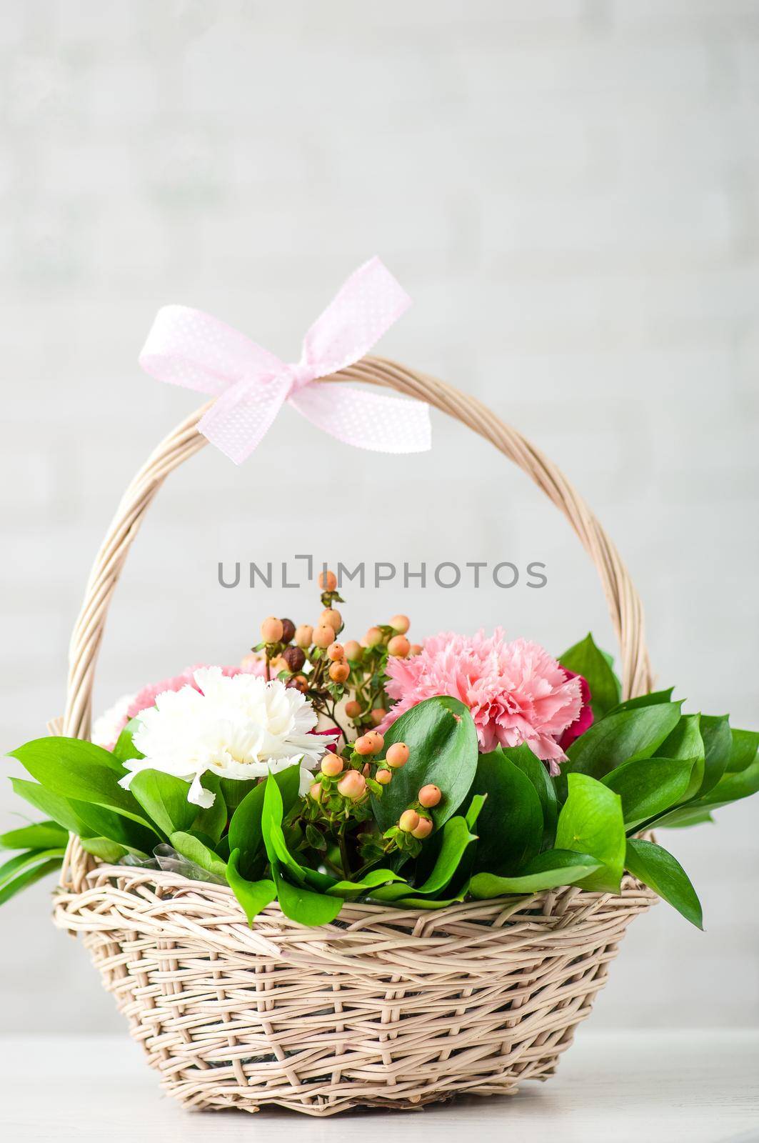 Vertical shot of a beautiful composition with white and pink peony roses in a straw basket by A_Karim