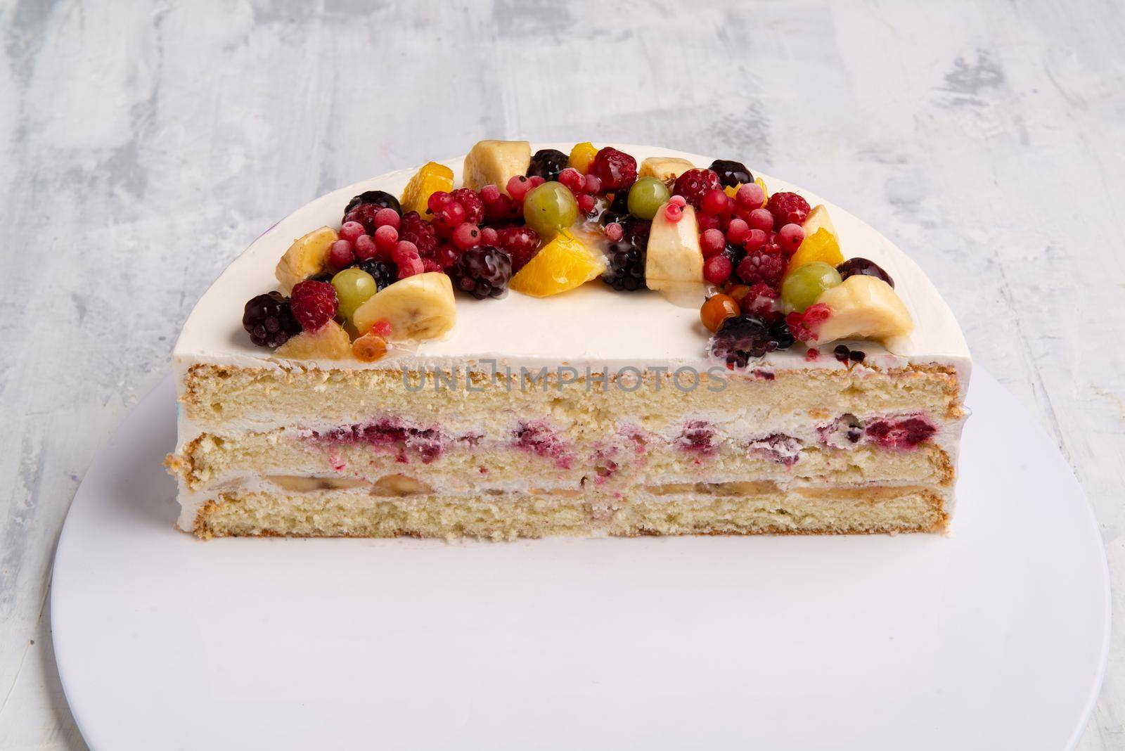 A top view shot of sliced half fruit cake on a white plate